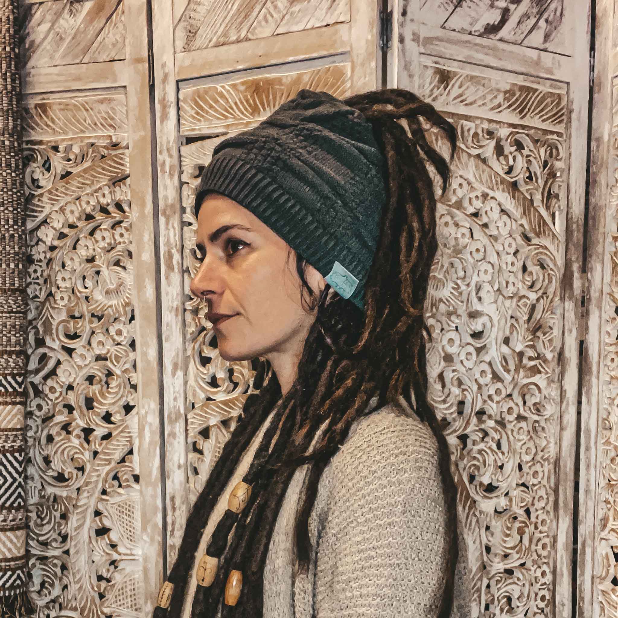 Side view of a dark grey CrafterElena Squares beanie worn with locs