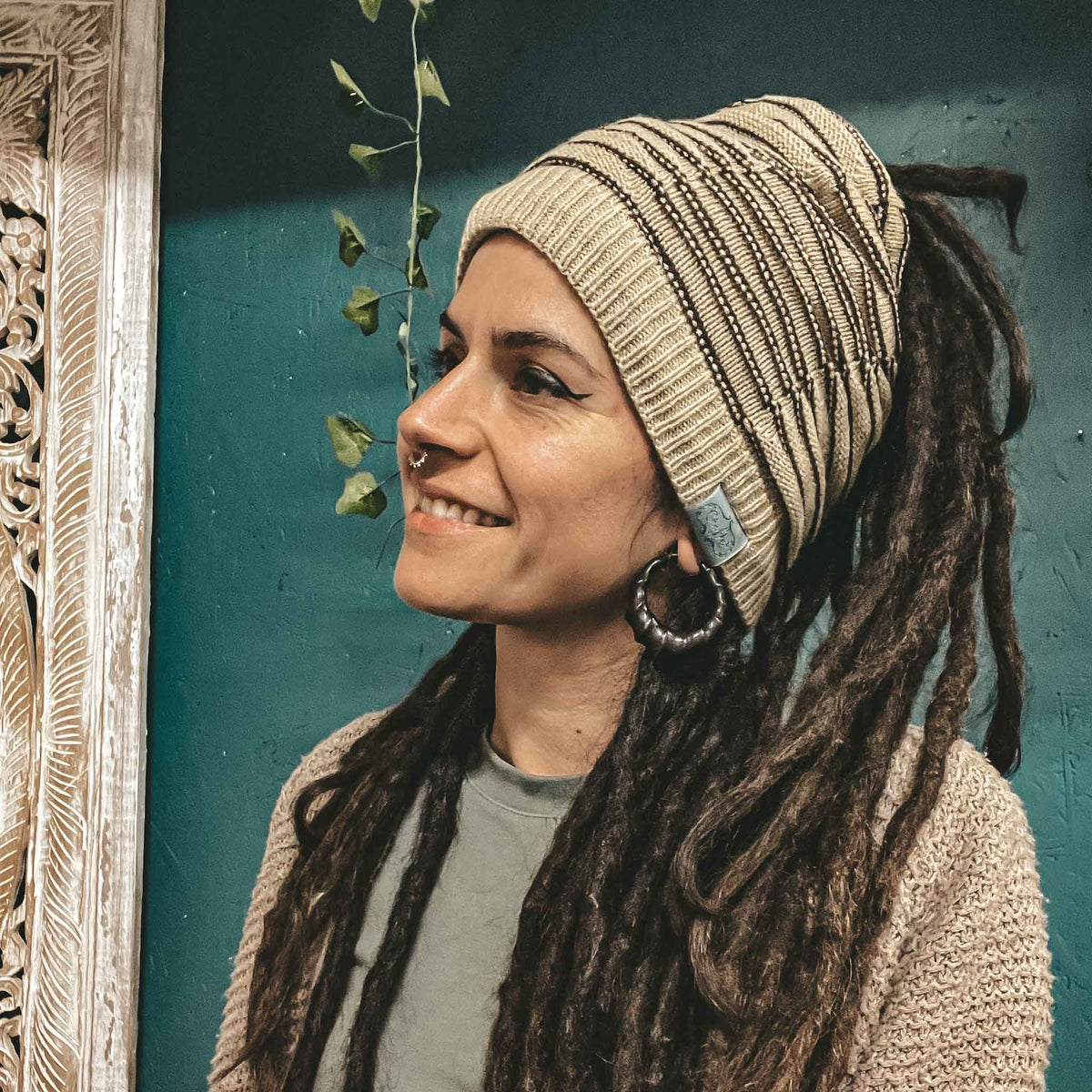 Person wearing a beige CrafterElena Striped beanie with locs