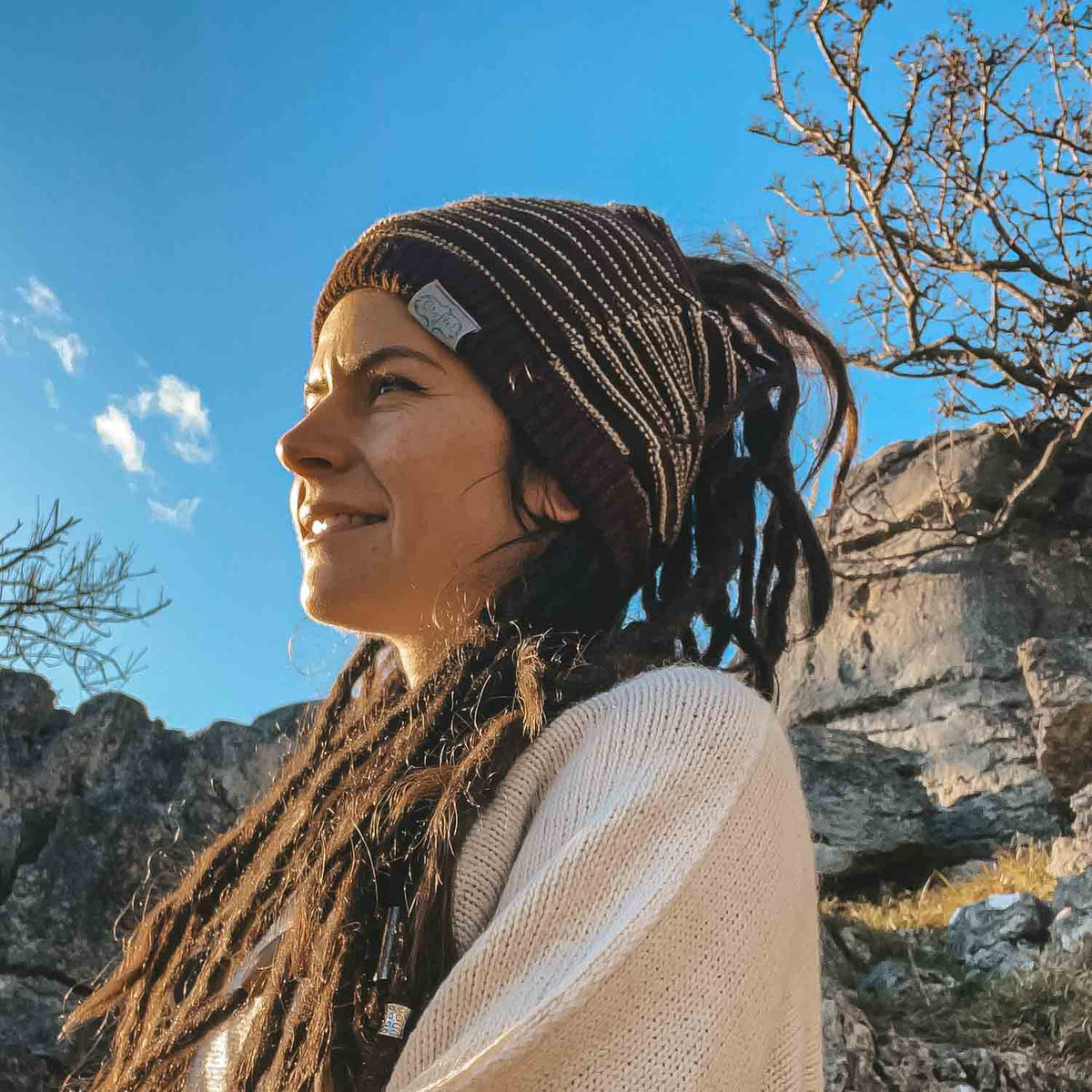 Person wearing a dark brown CrafterElena Striped beanie with locs