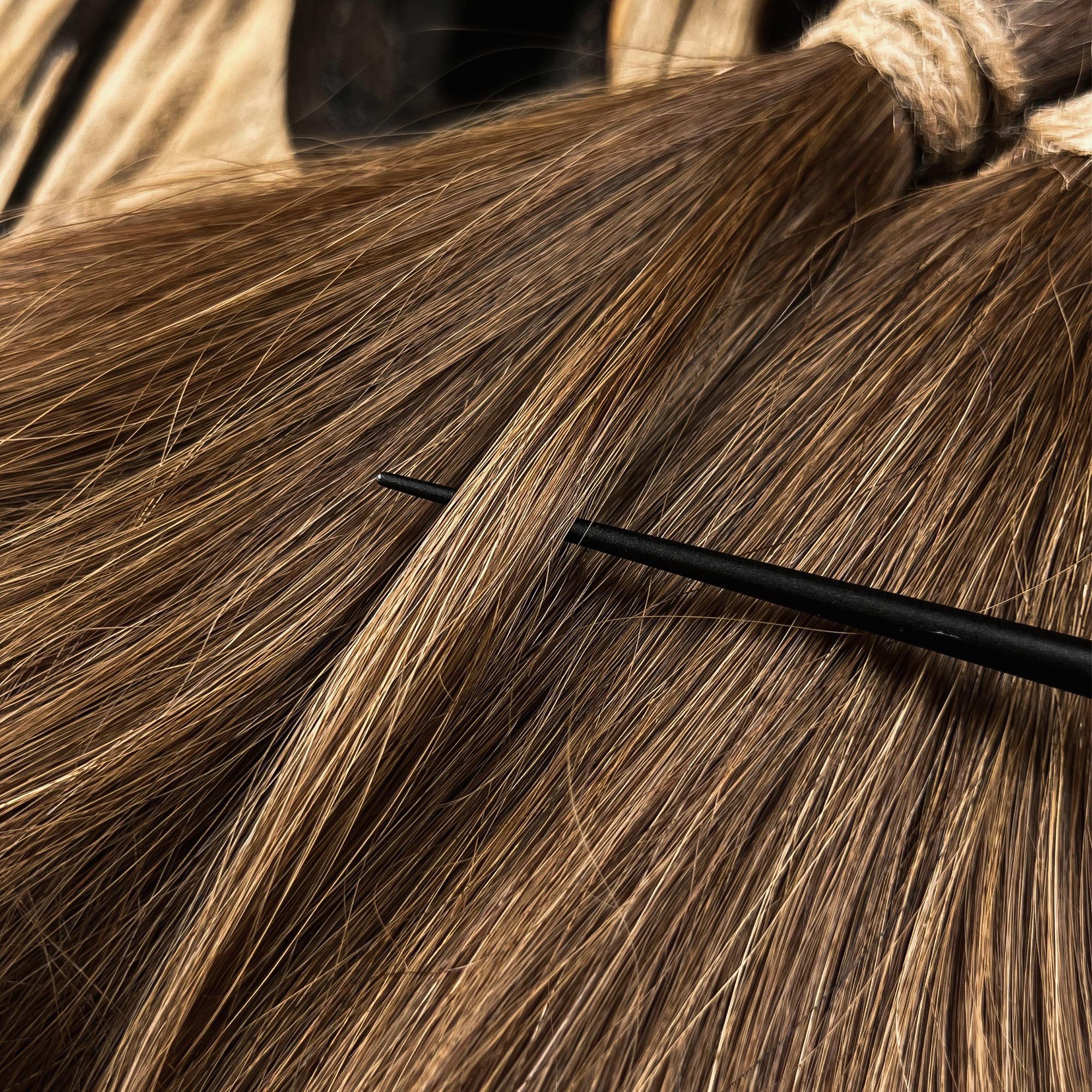 Close-up of straight brown human hair being prepared with a tool for custom handmade Locs.