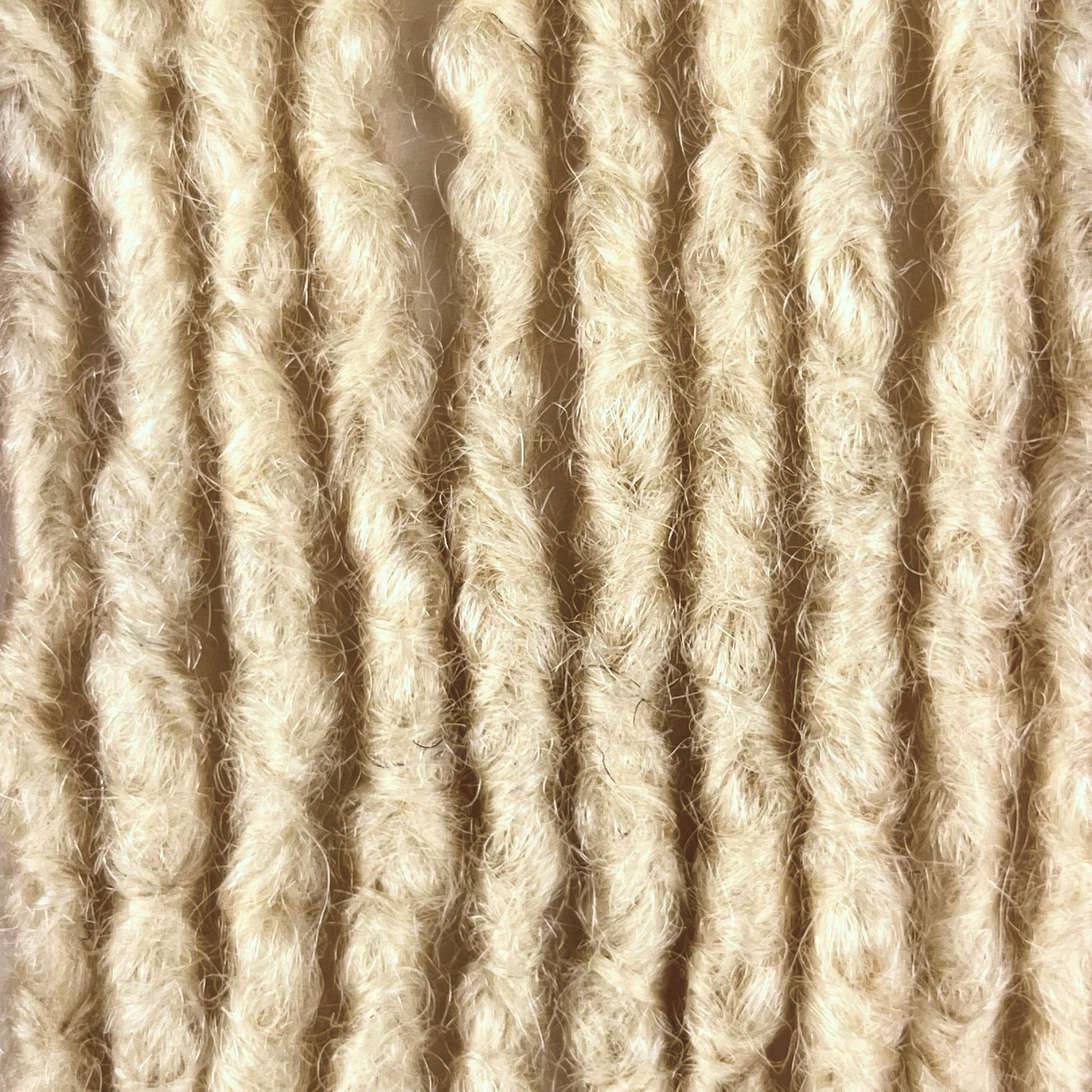 Close-up of Bleach Blonde kinky human hair loc extensions made using the interlocking method.