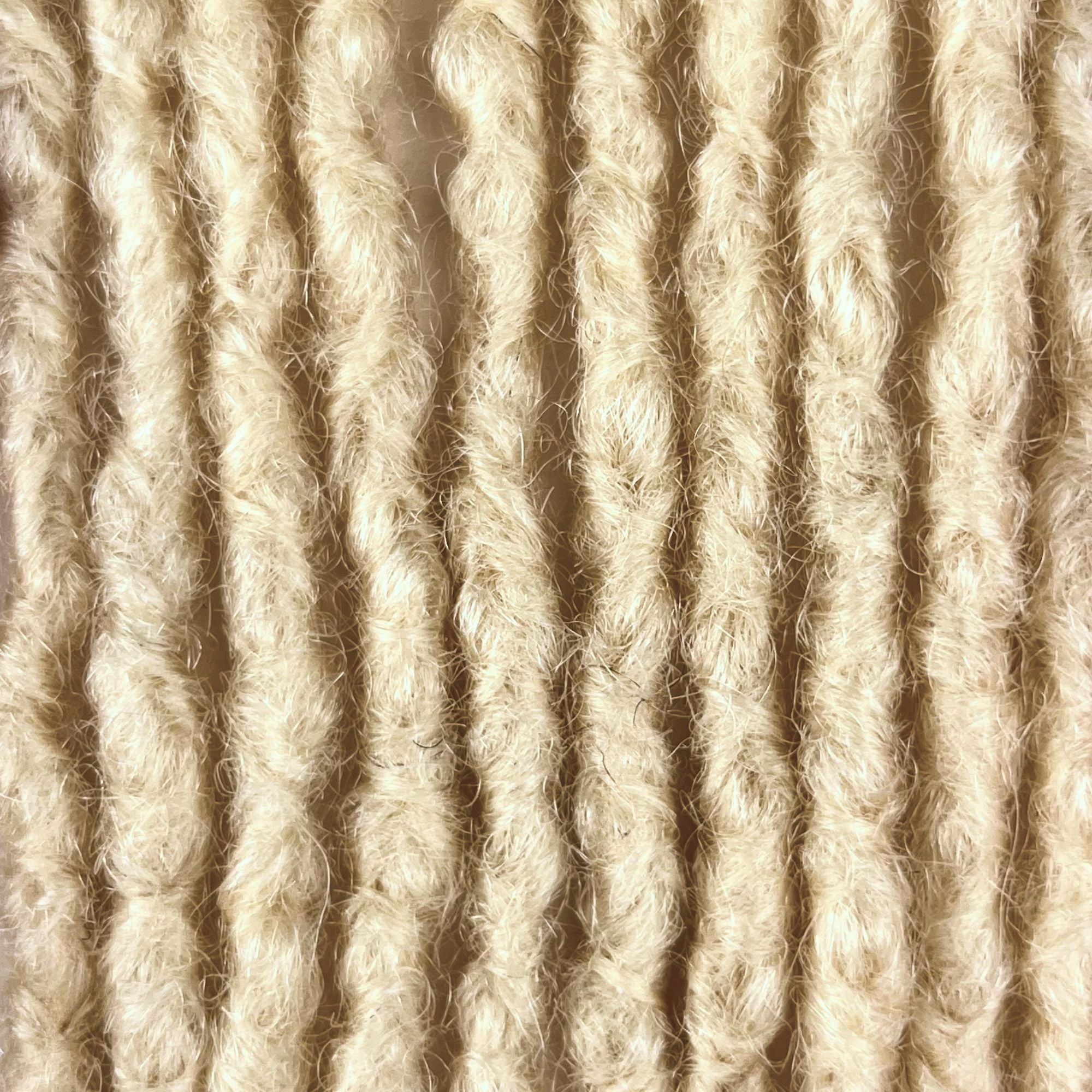 Close-up of Bleach Blonde kinky human hair loc extensions made using the interlocking method.