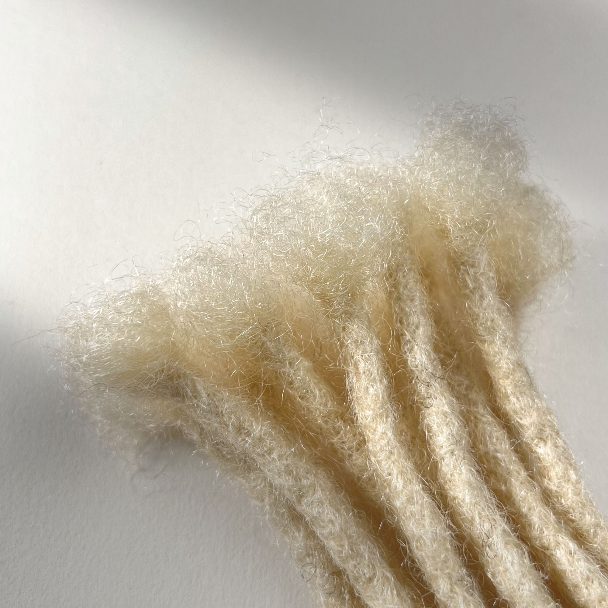 Close-up of the connection point on Bleach Blonde kinky human hair loc extensions.