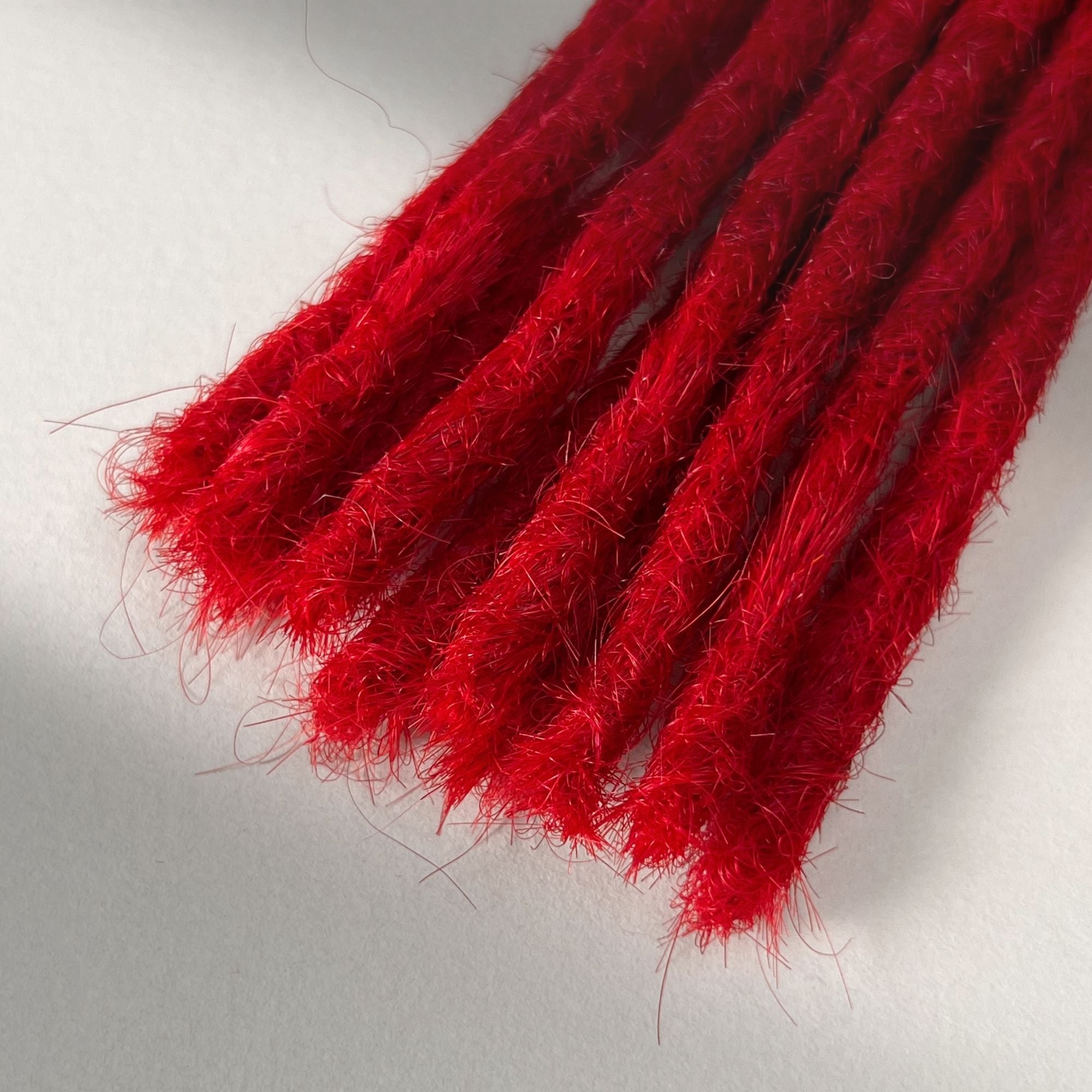 Tip detail of straight loc extensions with blunt ends in Flame Red.
