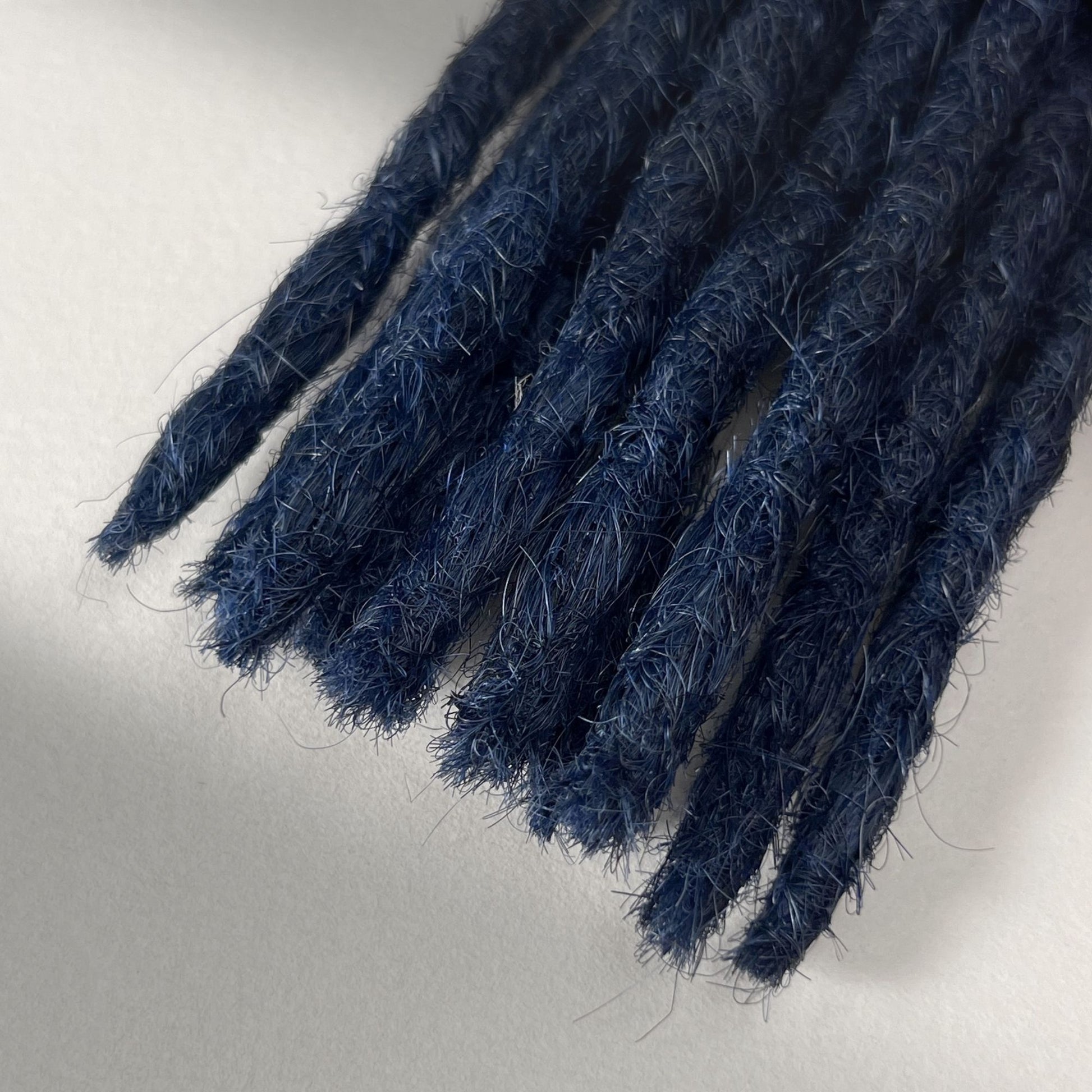 Tip detail of straight loc extensions with blunt ends in Midnight Blue.