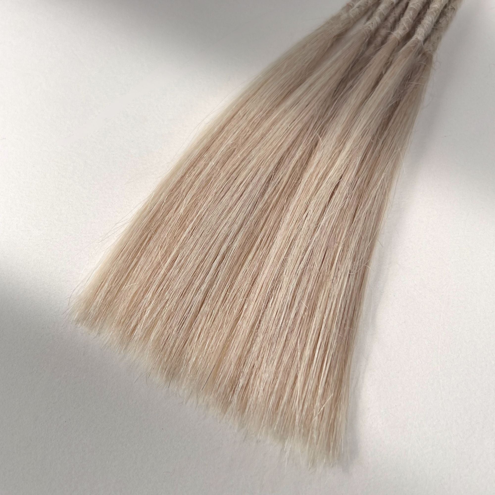 Tip detail of straight loc extensions with long loose ends in Cool Ash Blonde.