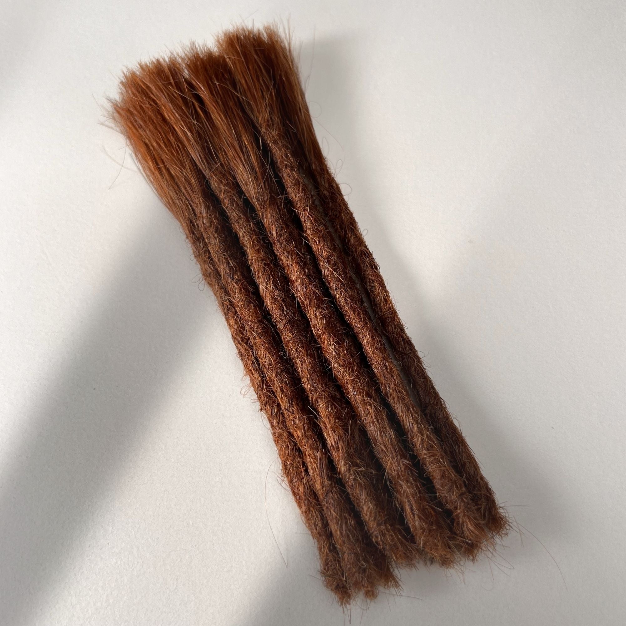 Full view of permanent straight loc extensions with blunt ends in Burnt Sienna Copper.