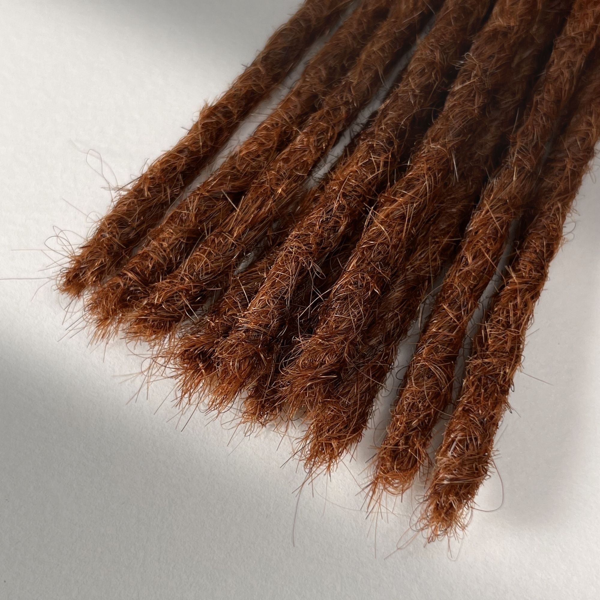 Tip detail of straight loc extensions with blunt ends in Burnt Sienna Copper.