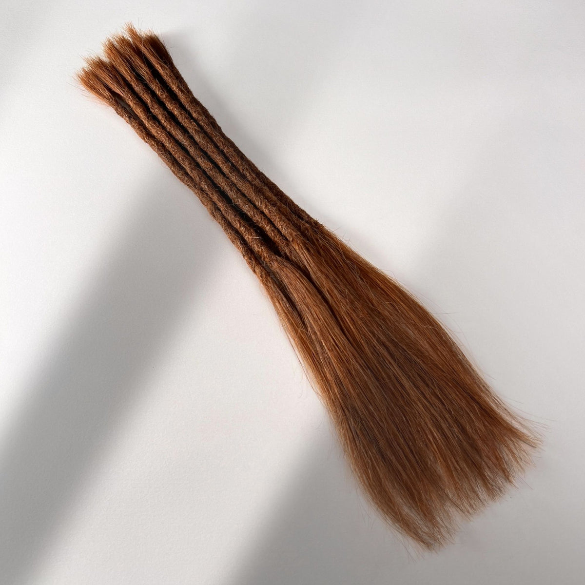Full view of permanent straight loc extensions with long loose ends in Burnt Sienna Copper.