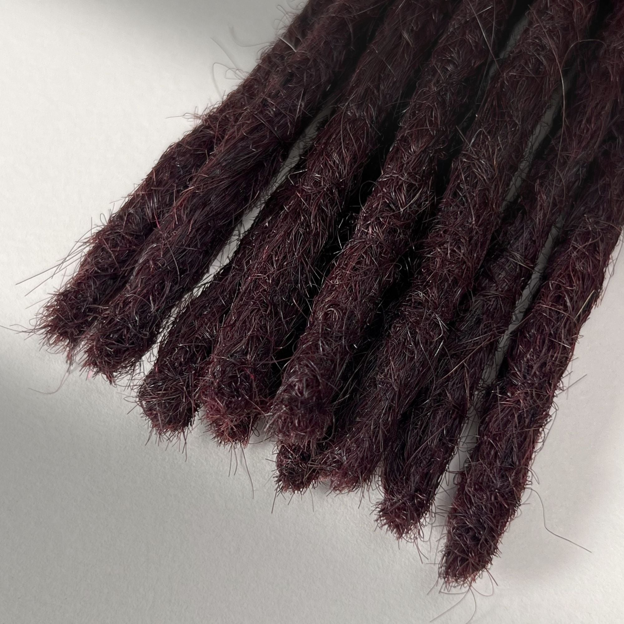Tip detail of straight loc extensions with blunt ends in Deep Crimson Red.