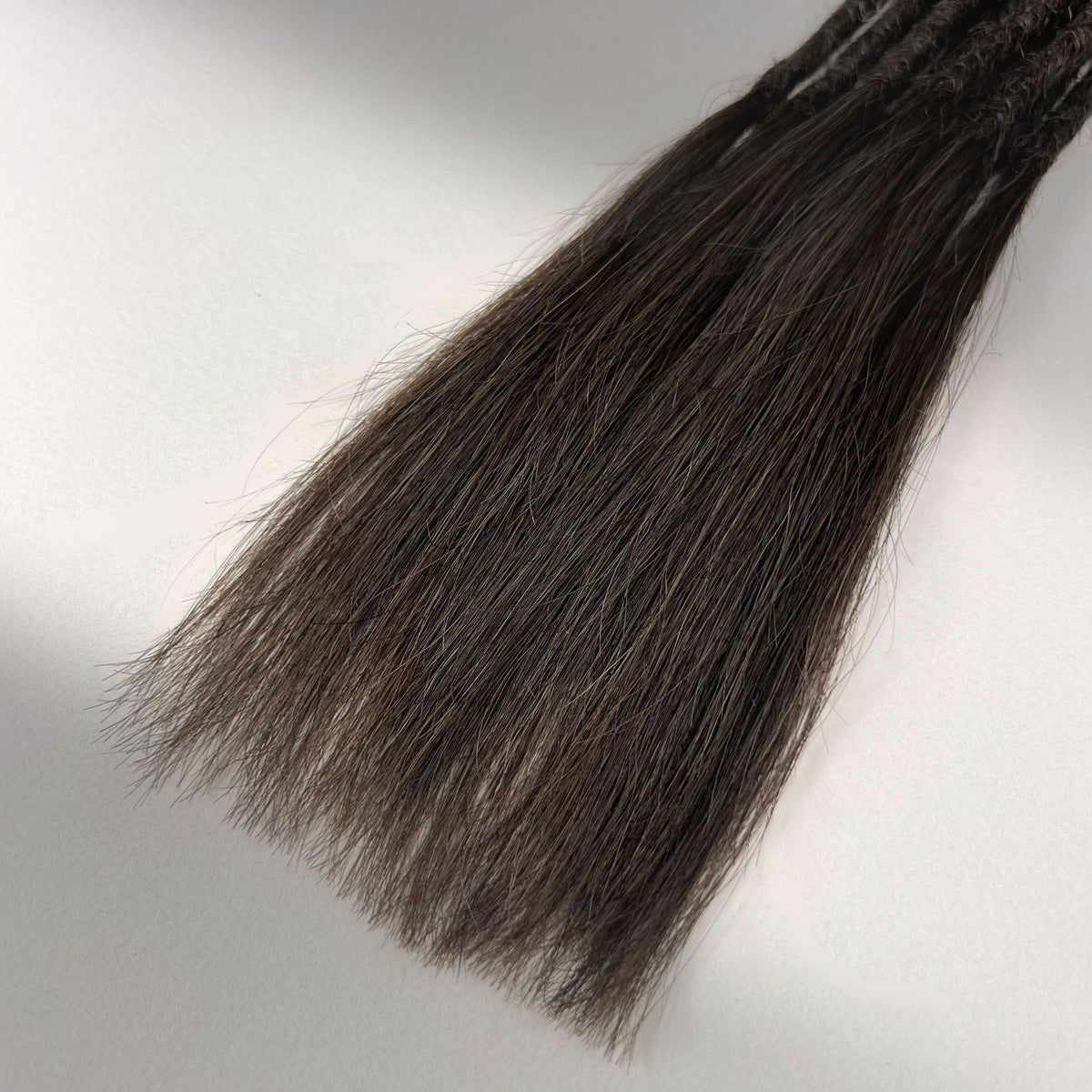 Tip detail of straight loc extensions with long loose ends in Dark Wenge Brown.