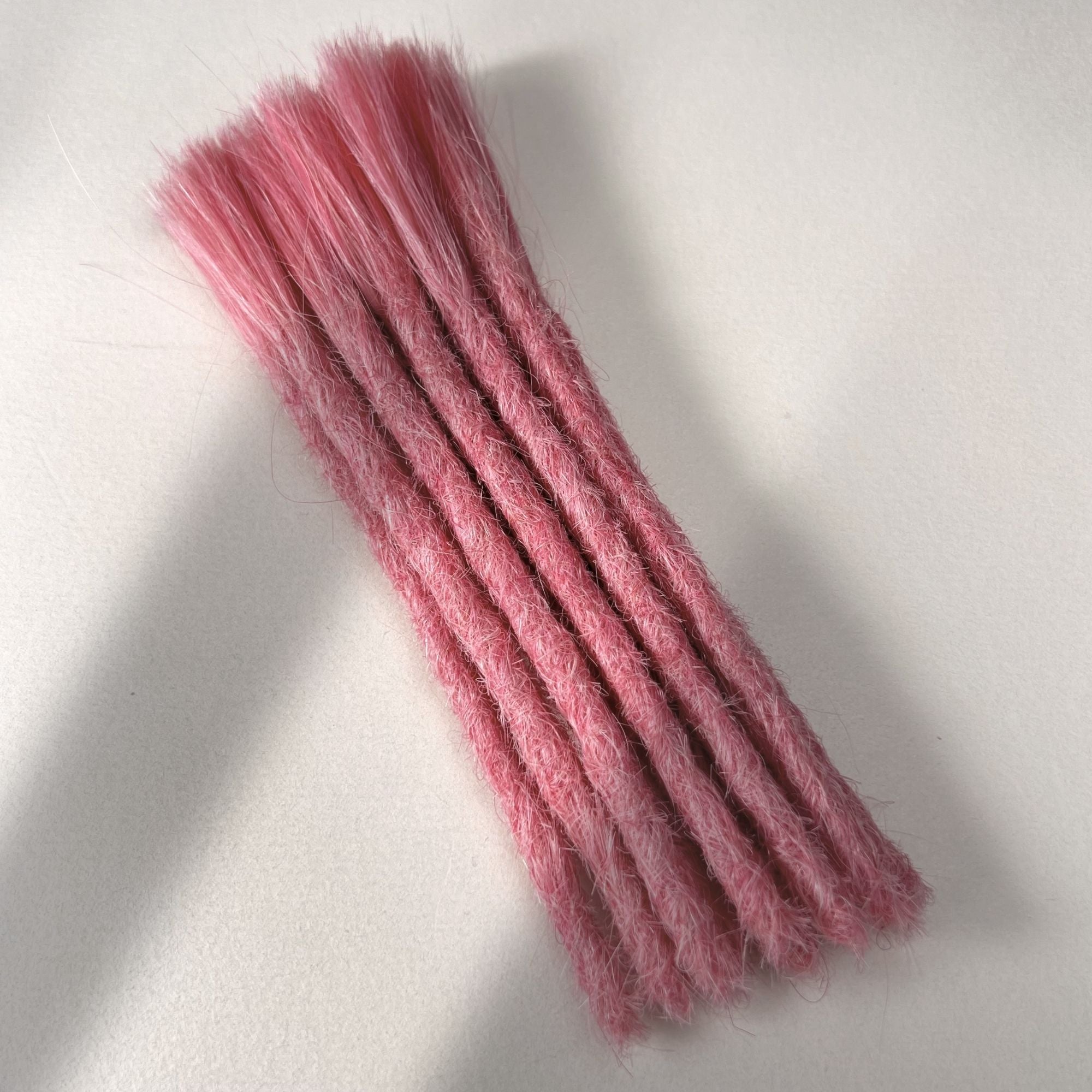 Full view of permanent straight loc extensions with blunt ends in Bubblegum Pink.