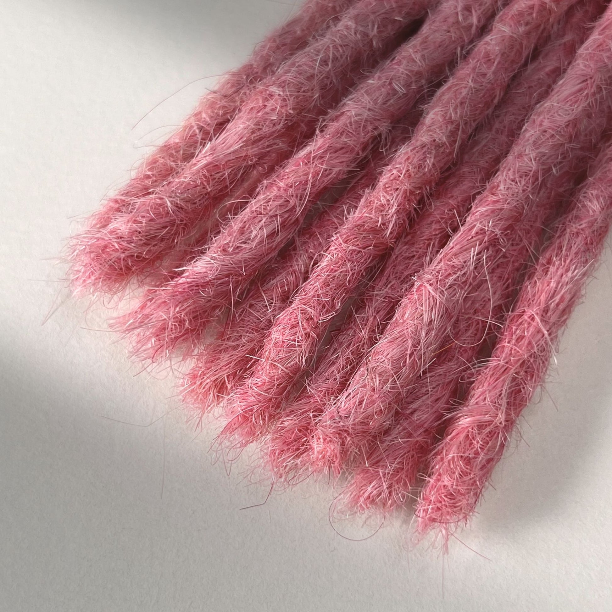 Tip detail of straight loc extensions with blunt ends in Bubblegum Pink.