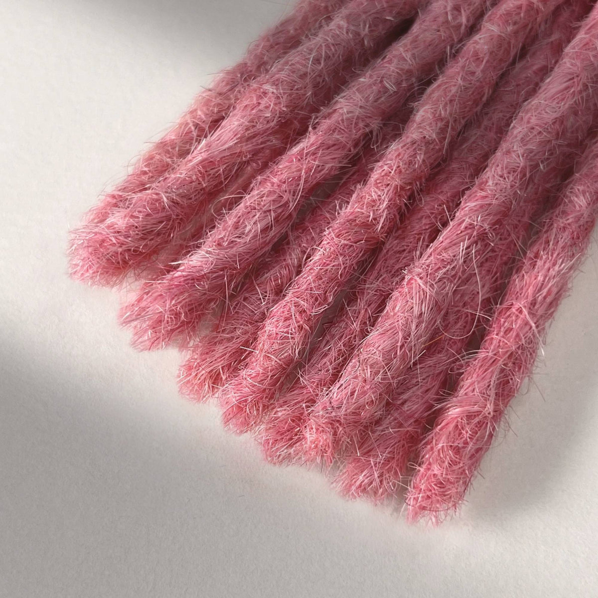 Tip detail of straight loc extensions with blunt ends in Bubblegum Pink.