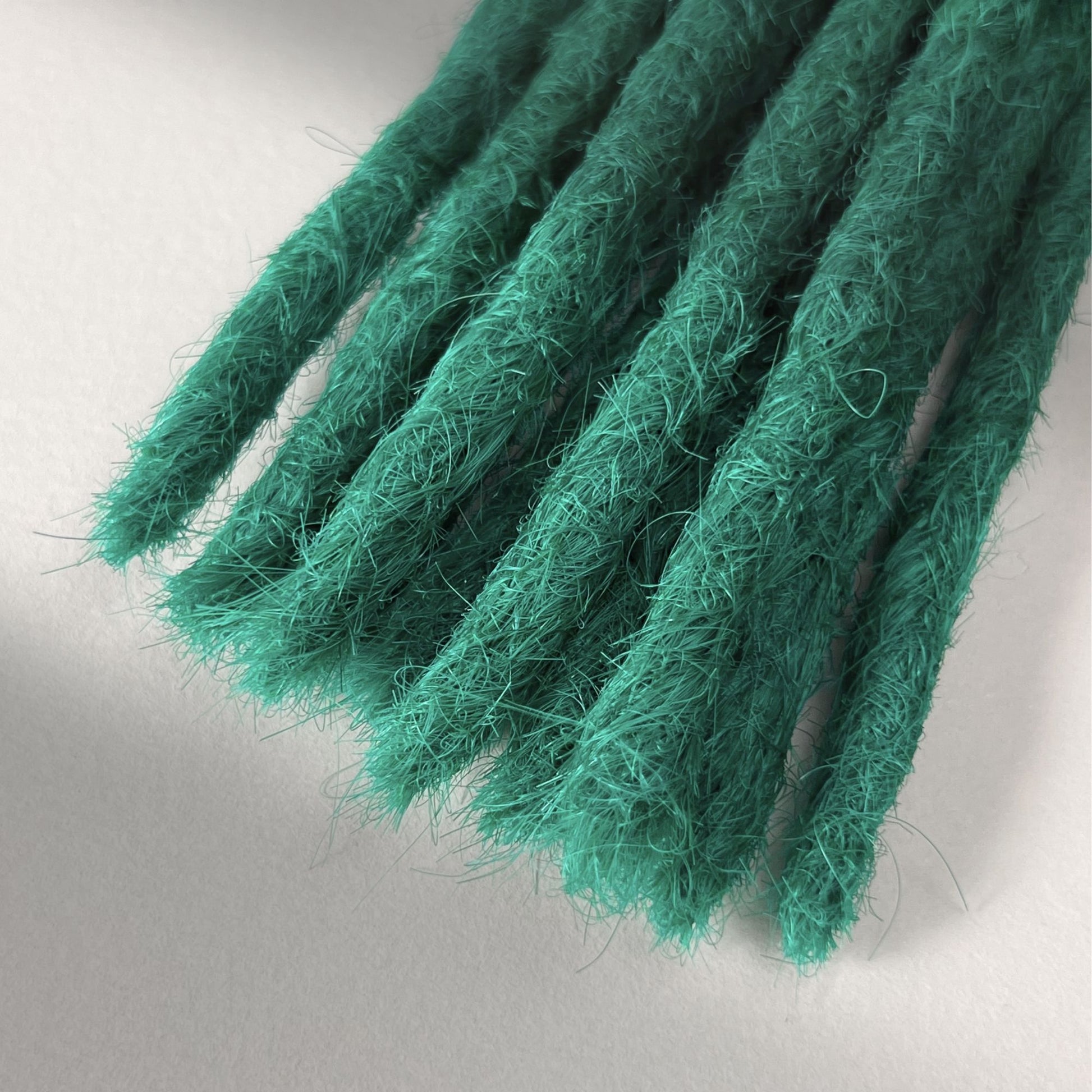 Tip detail of straight loc extensions with blunt ends in Emerald Green.