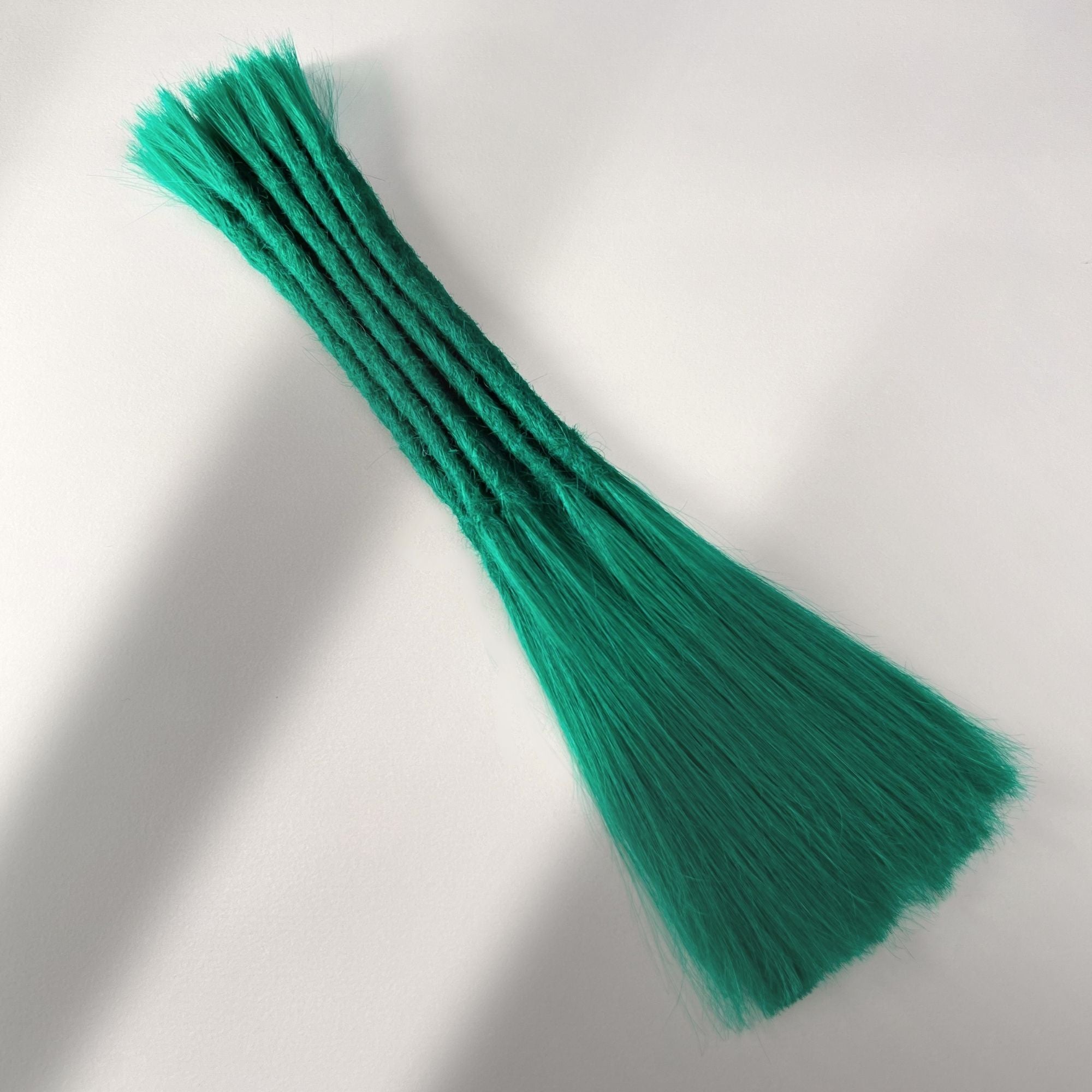 Full view of permanent straight loc extensions with long loose ends in Emerald Green.