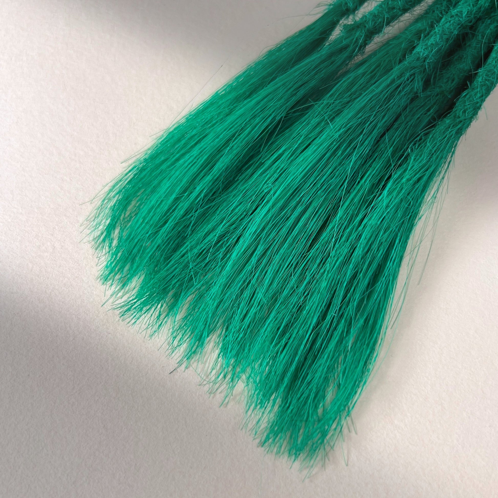 Tip detail of straight loc extensions with open ends in Emerald Green.