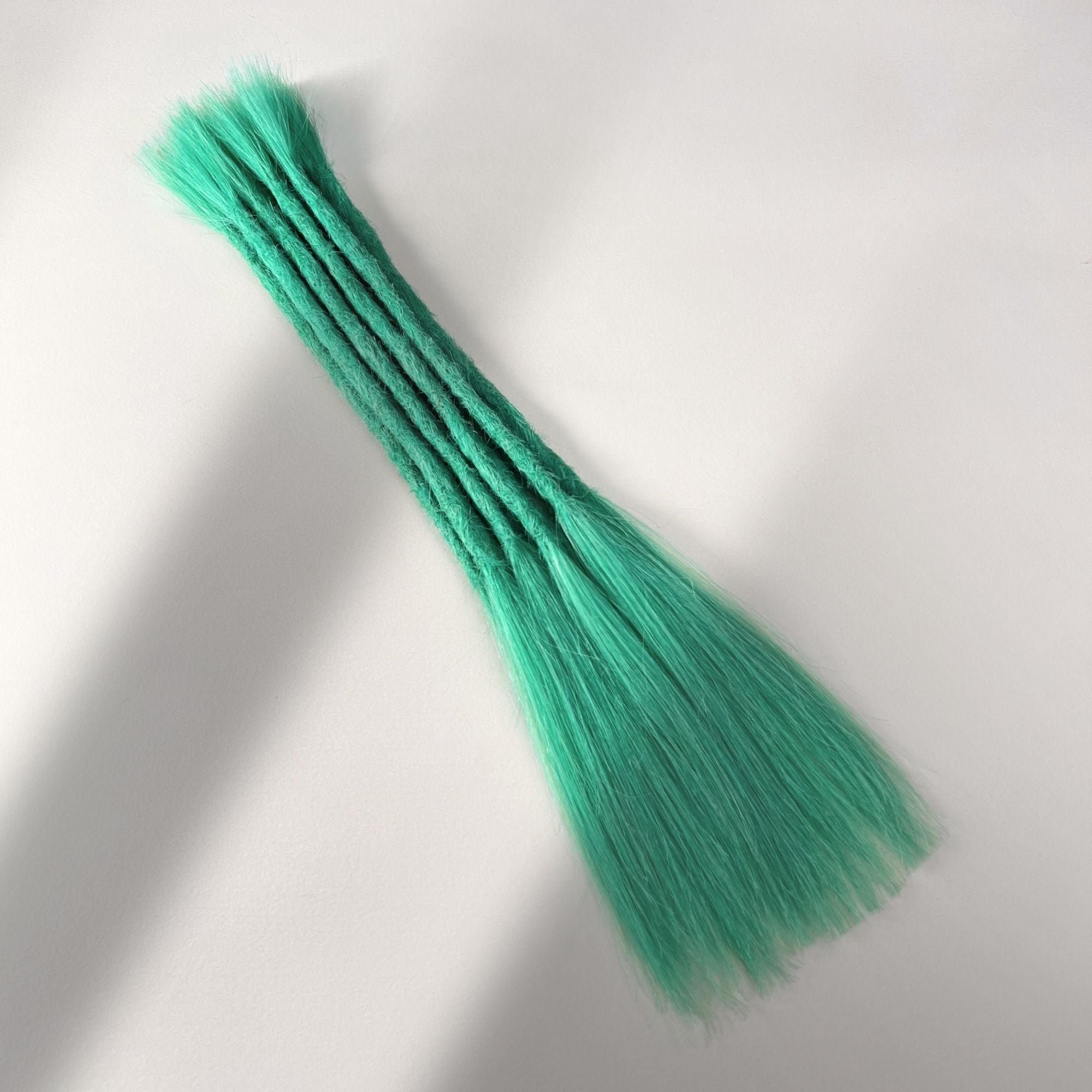 Full view of permanet straight loc extensions with long loose ends in Pastel Emerald Green.