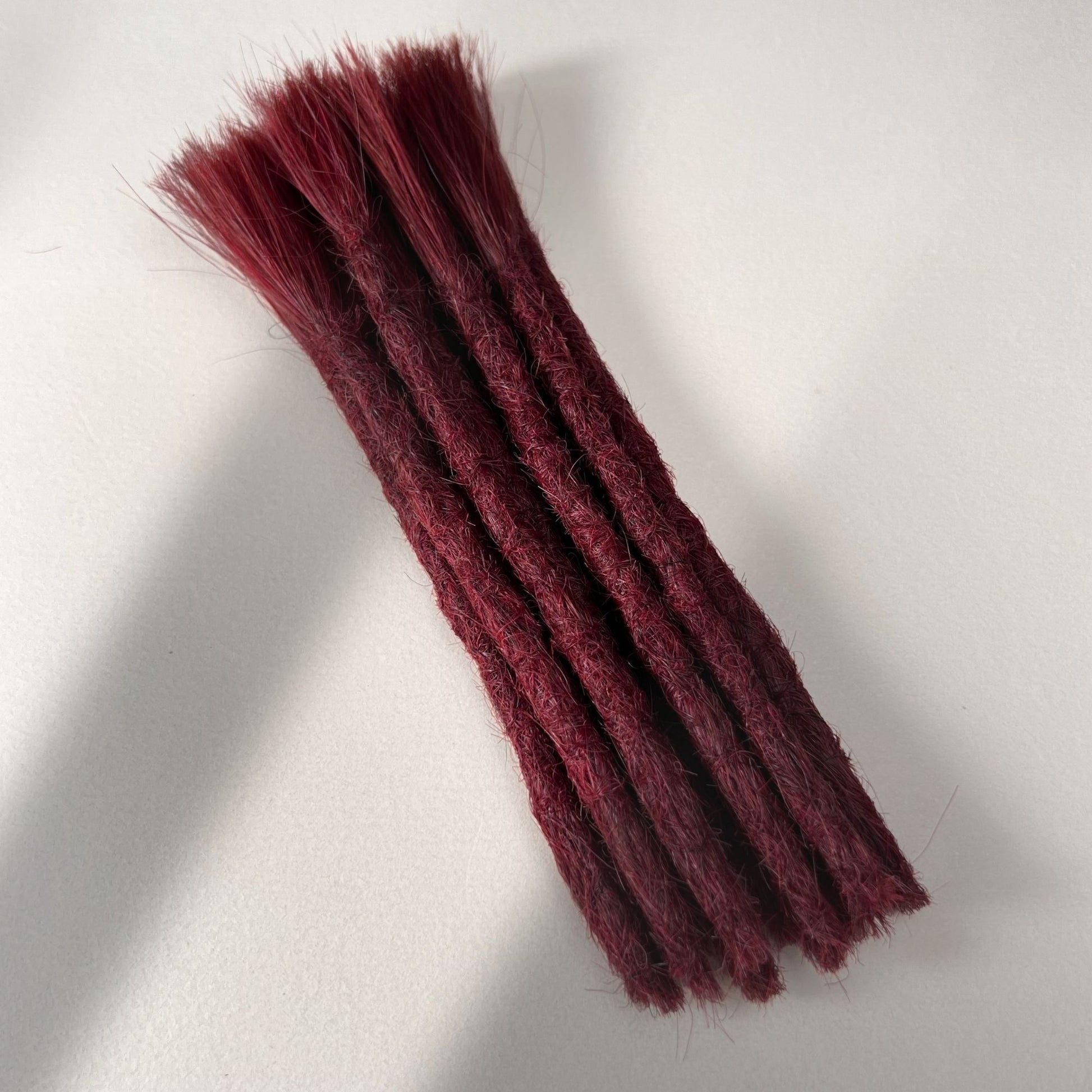 Full view of permanent straight loc extensions with blunt ends in Deep Garnet Red.