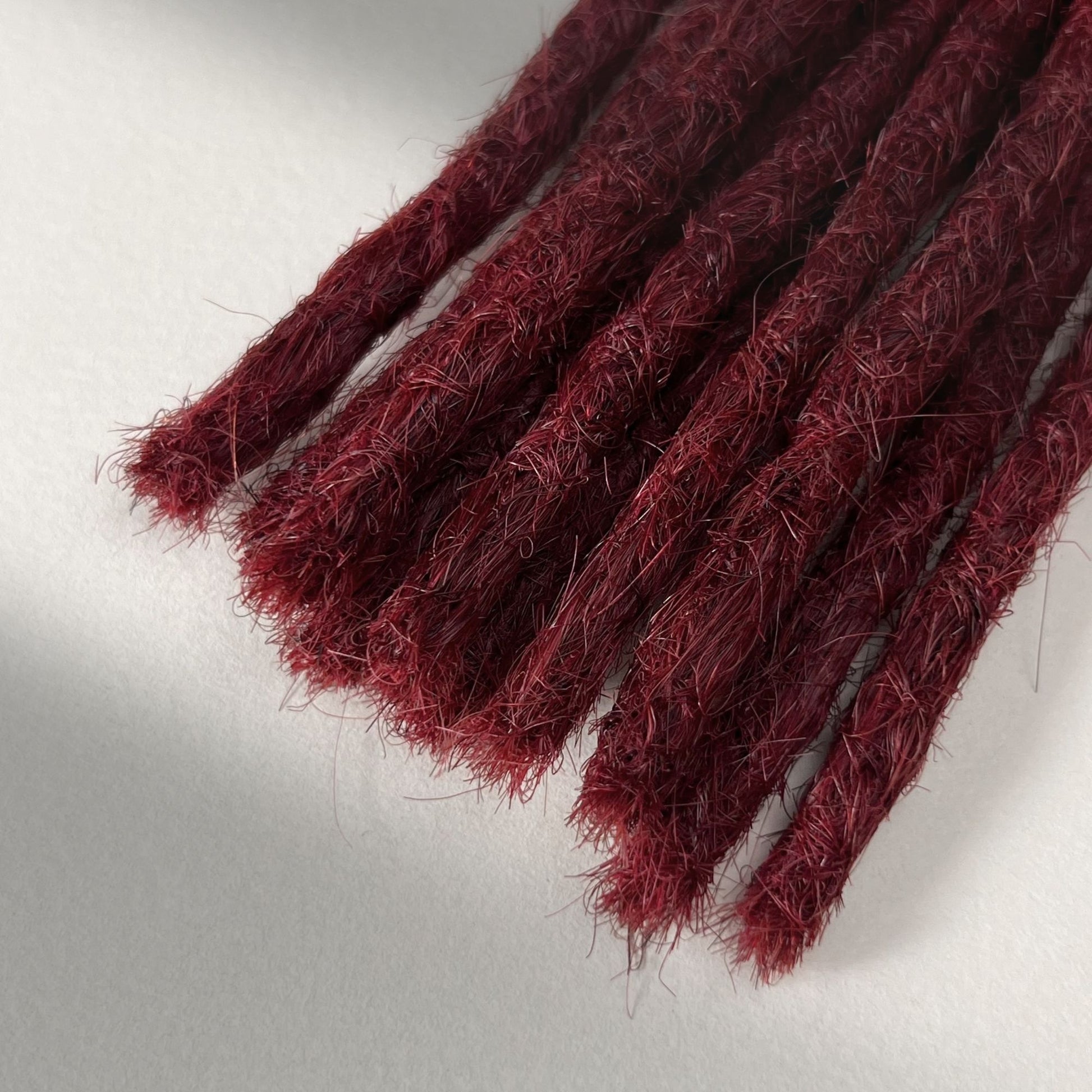 Tip detail of straight loc extensions with blunt ends in Deep Garnet Red.