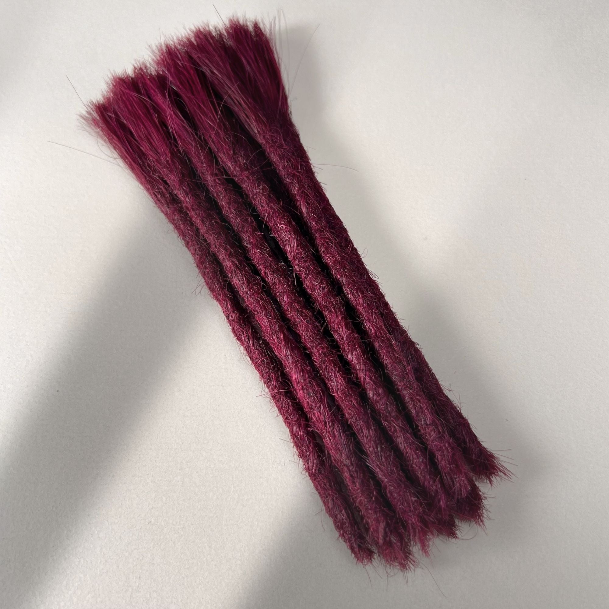 Full view of permanent straight loc extensions with blunt ends in Dark Cherry Red.
