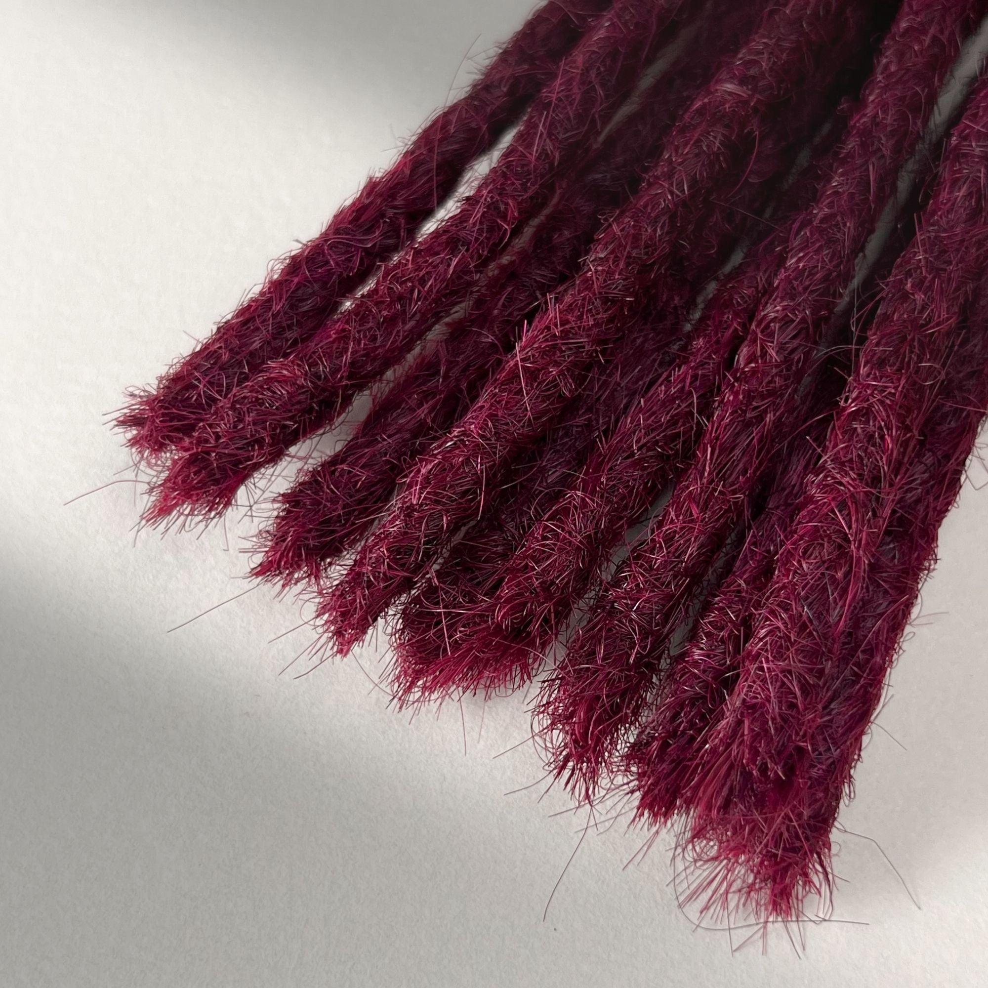 Tip detail of straight loc extensions with blunt ends in Dark Cherry Red.