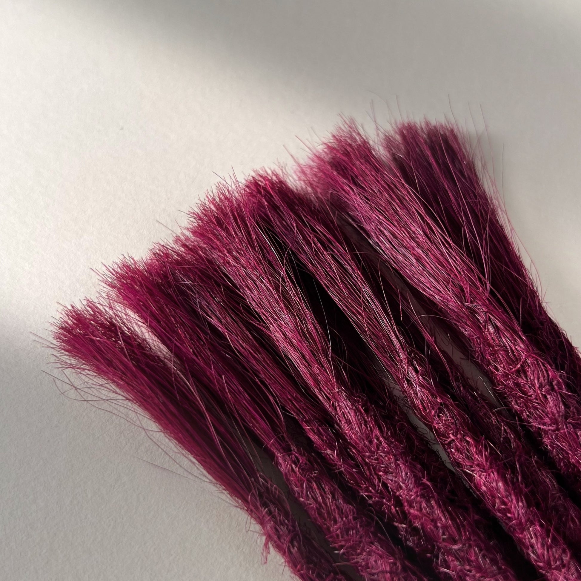 Connection point of permanent straight loc extensions in Dark Cherry Red.