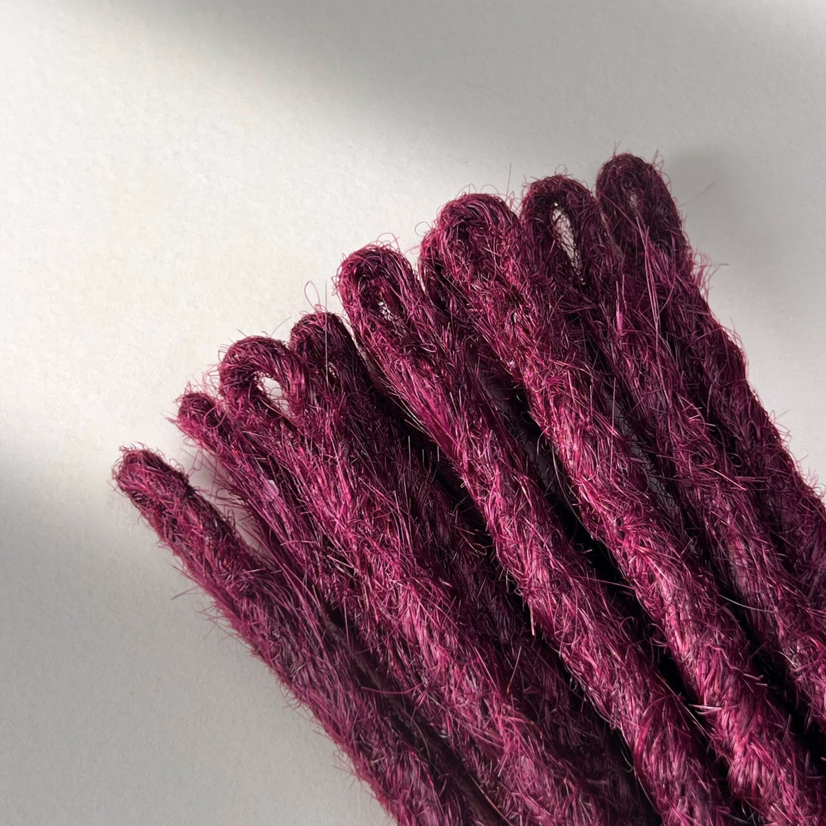 Loop detail of temporary single-ended straight loc extensions in Dark Cherry Red.