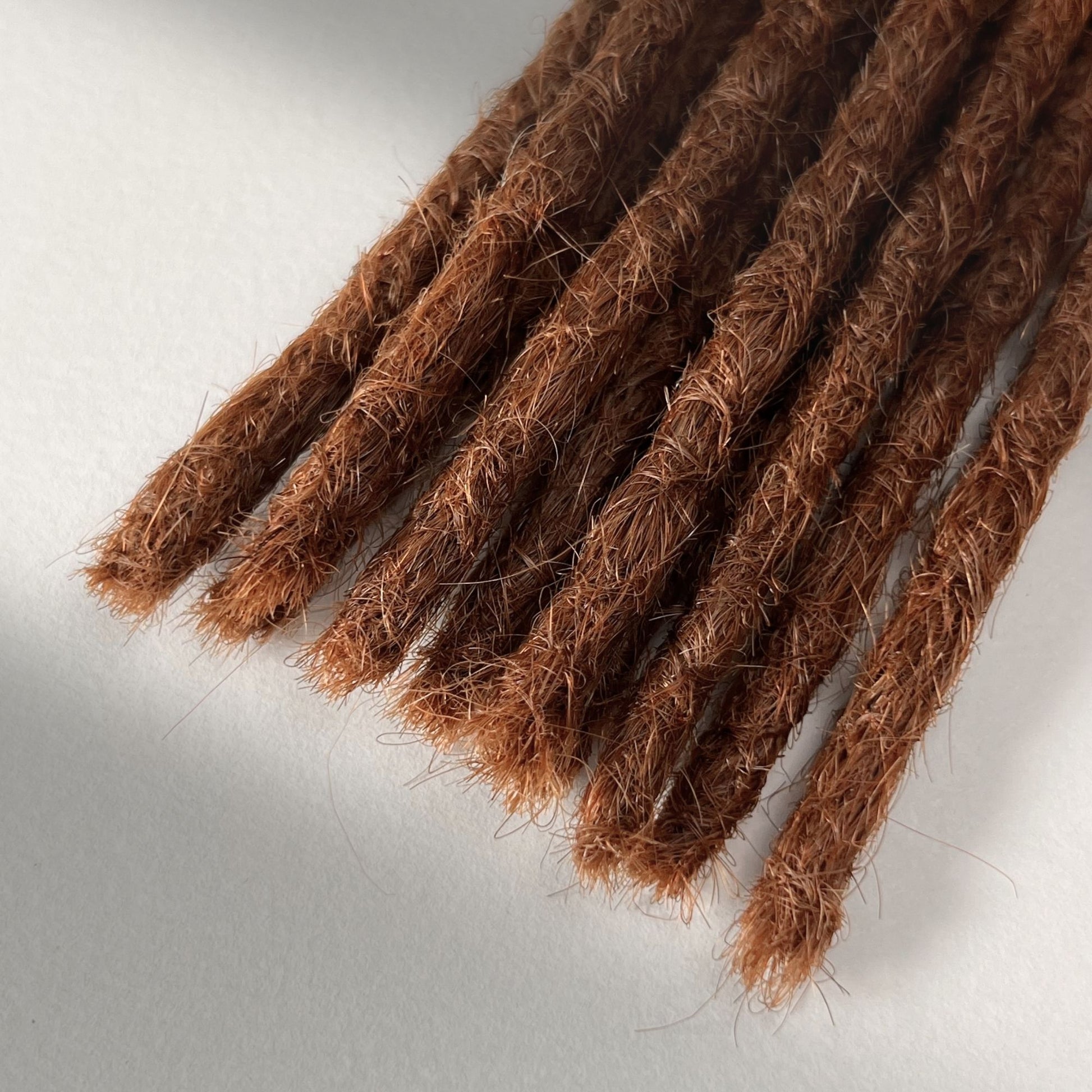 Tip detail of straight loc extensions with blunt ends in Burnt Copper.