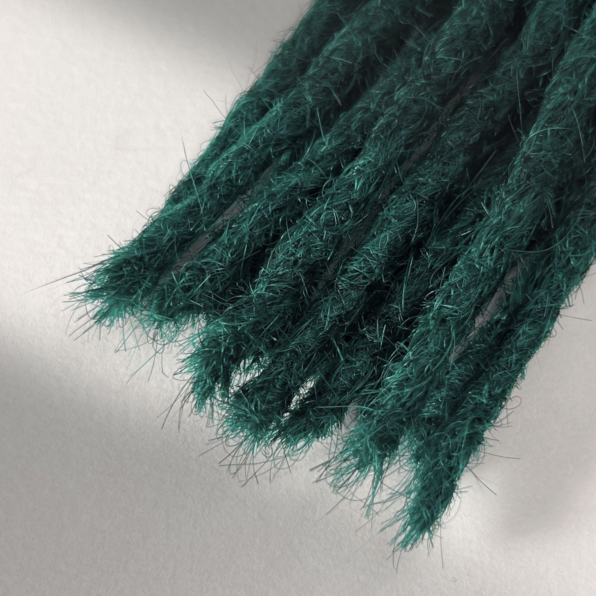 Tip detail of straight loc extensions with blunt ends in Forest Green.