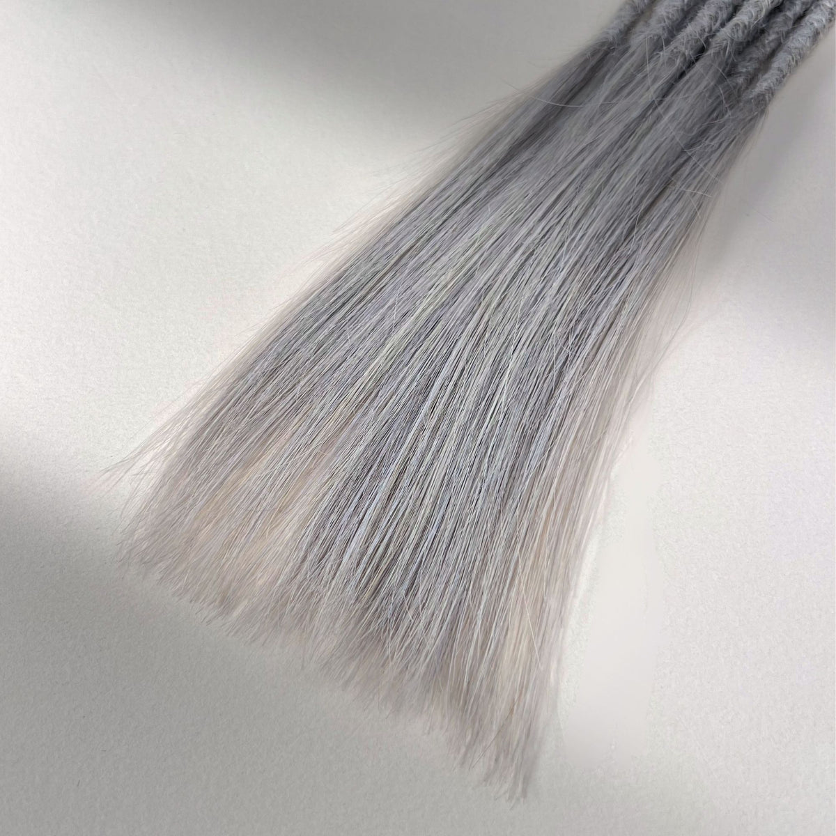 Tip detail of straight loc extensions with long loose ends in Pearl Silver.