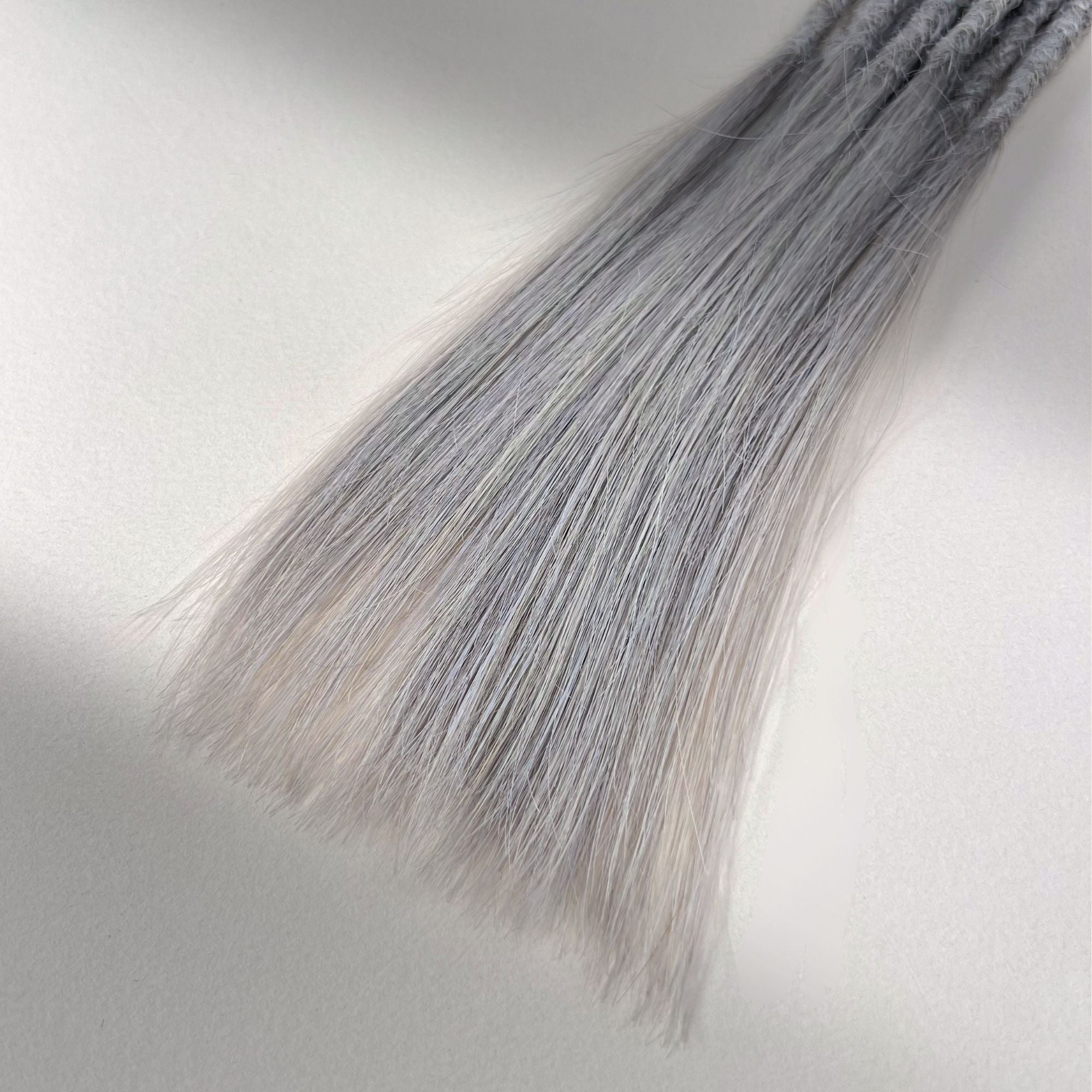 Tip detail of straight loc extensions with long loose ends in Pearl Silver.