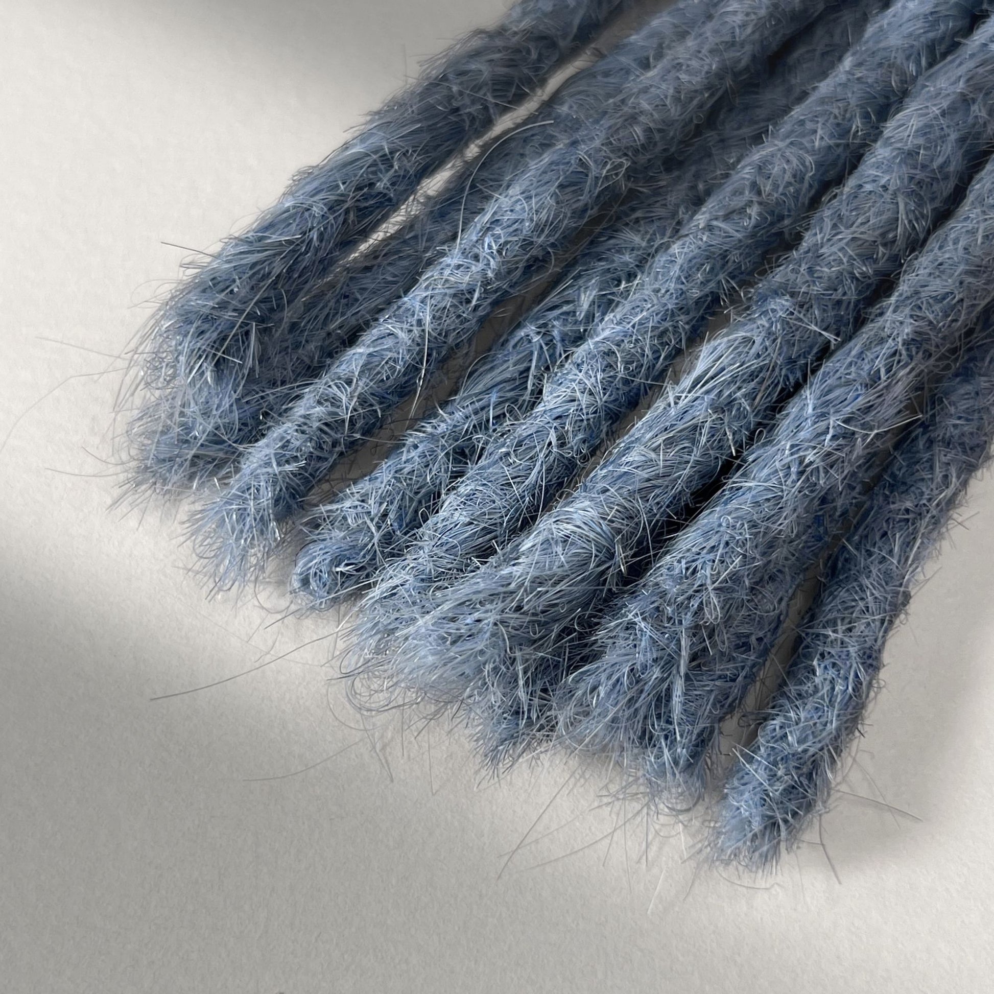 Tip detail of straight loc extensions with blunt ends in Sky Blue.
