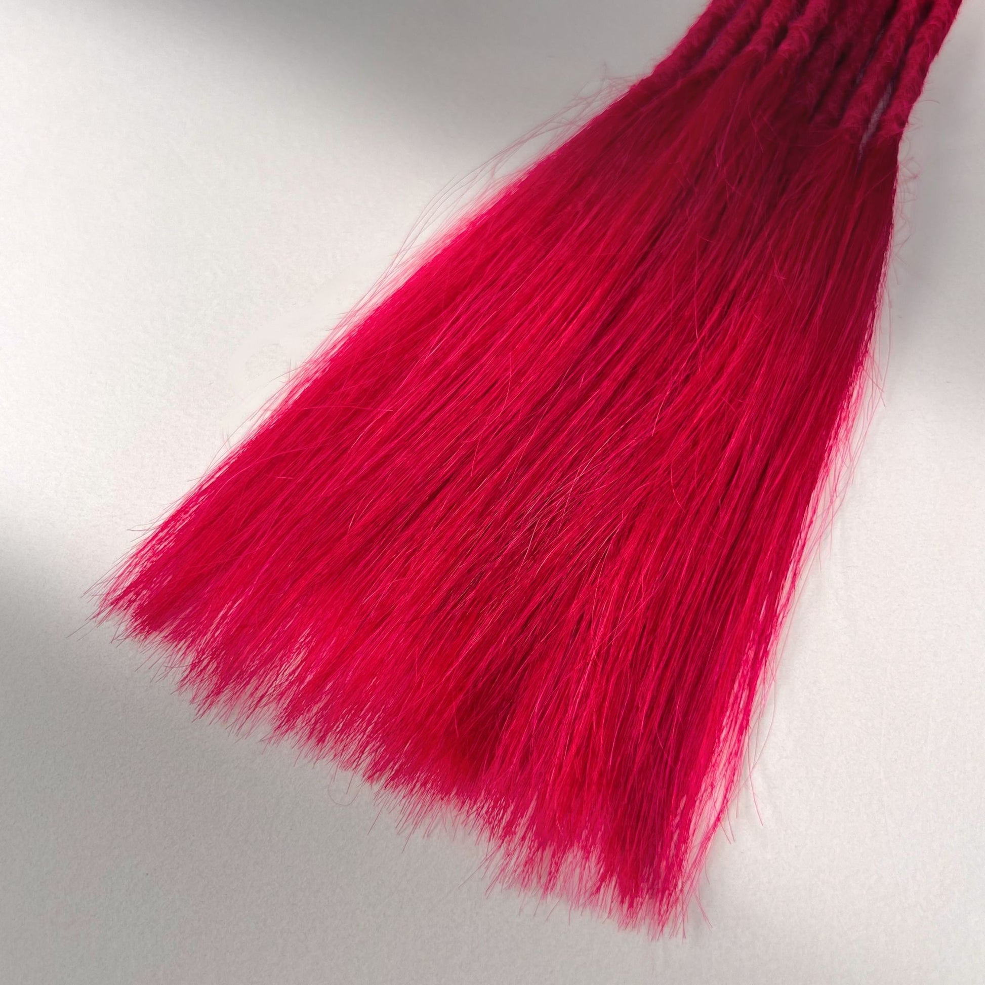 Tip detail of straight loc extensions with long vloose ends in Indian Pink.