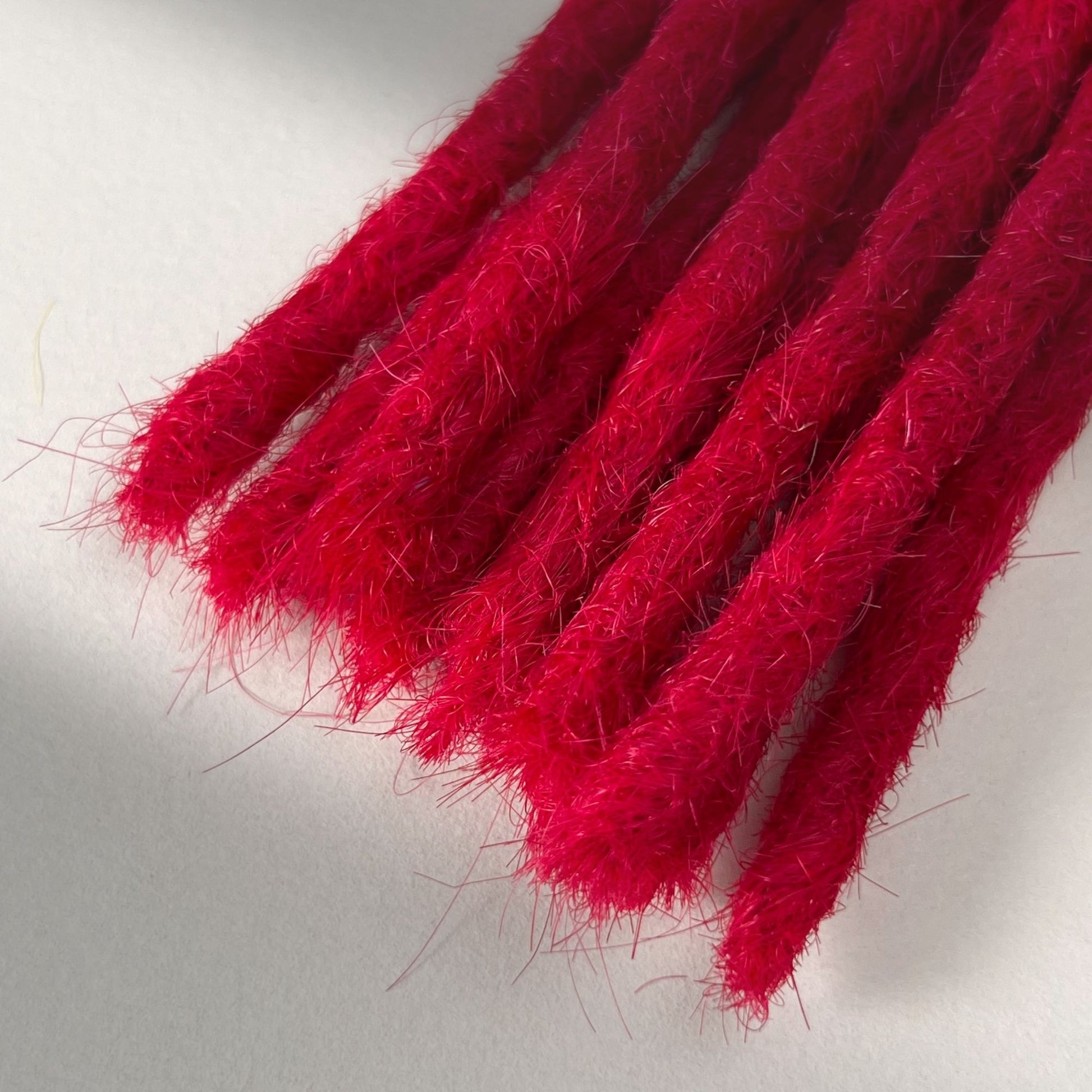 Tip detail of straight loc extensions with blunt ends in Indian Pink.