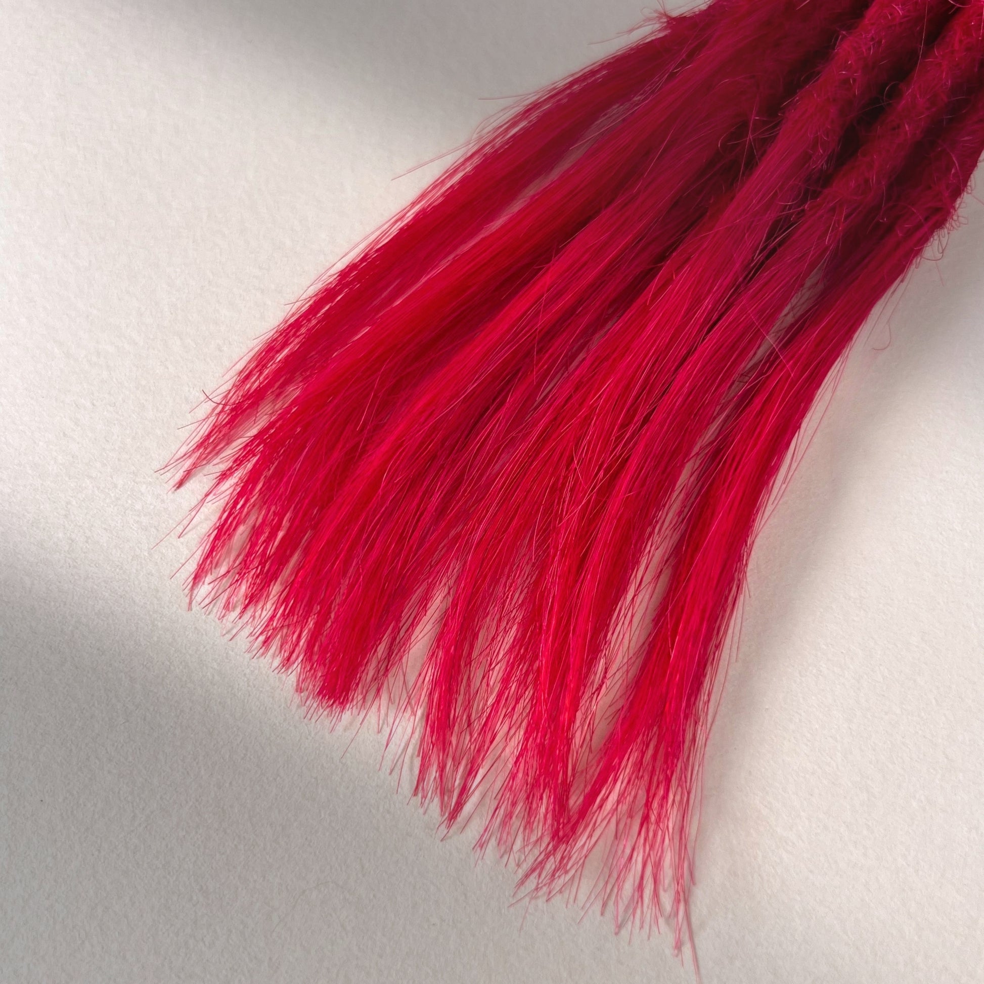 Tip detail of straight loc extensions with open ends in Indian Pink.