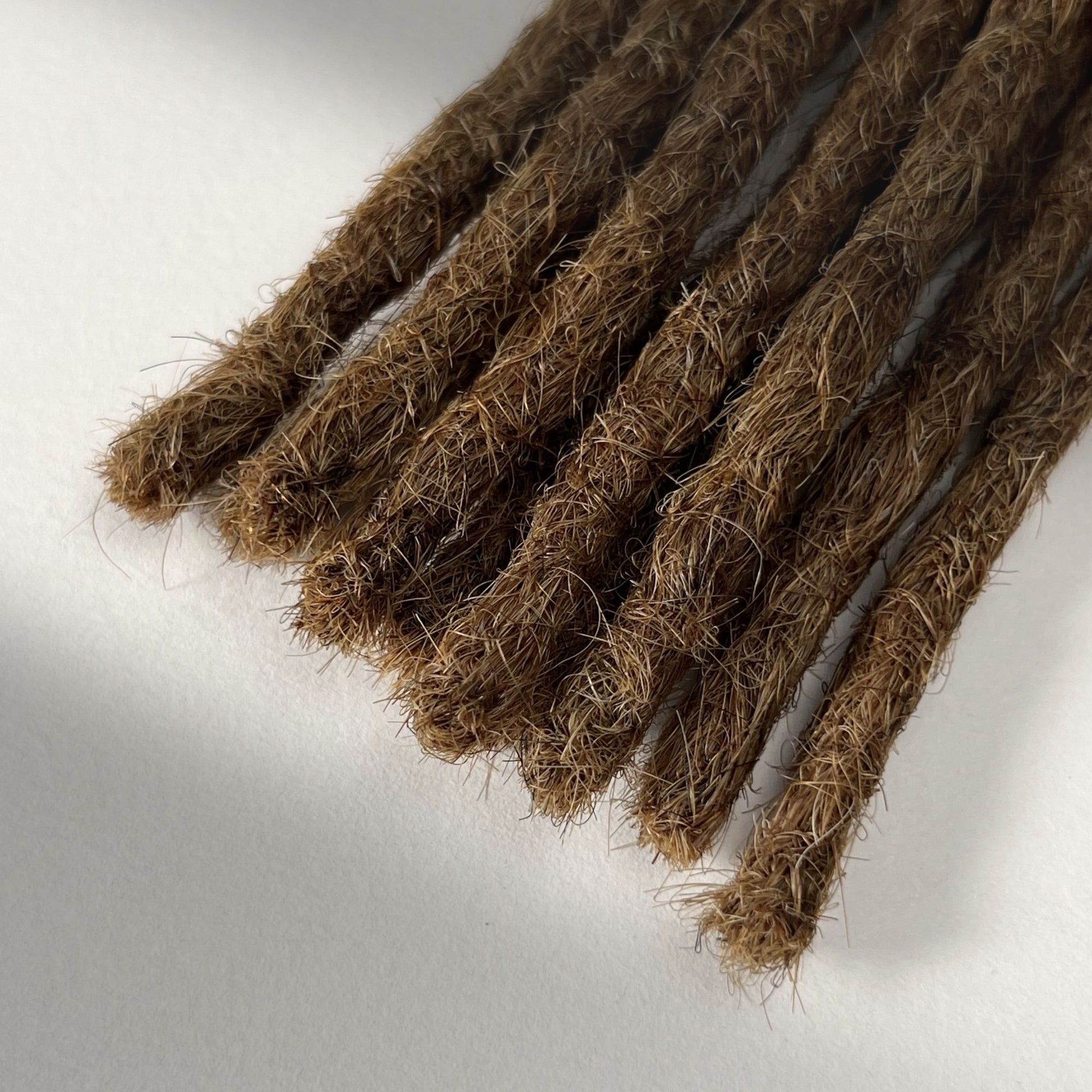 Tip detail of straight loc extensions with blunt ends in Honey Brown.