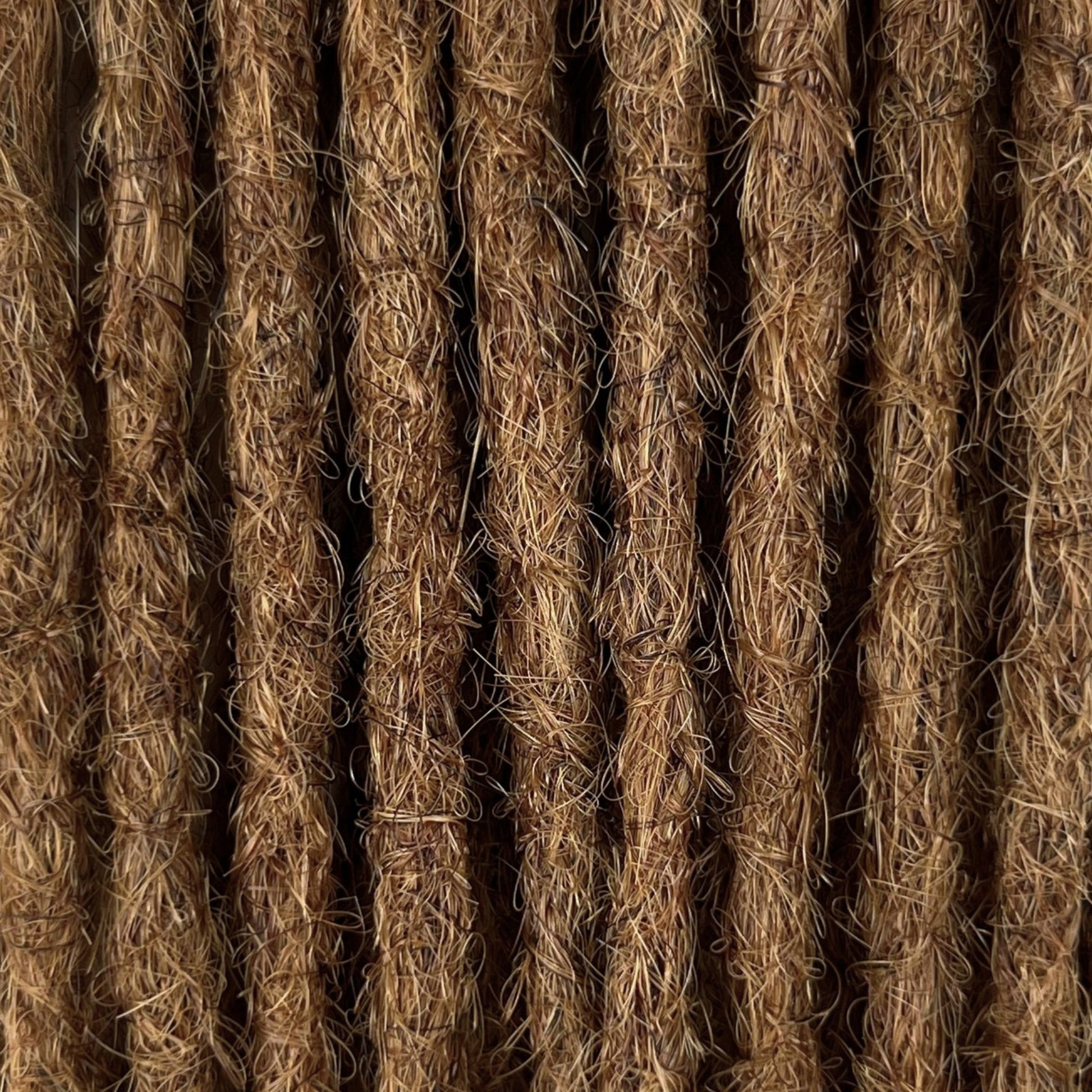 Close-up of straight loc extensions in Honey Brown, showing the texture and color.