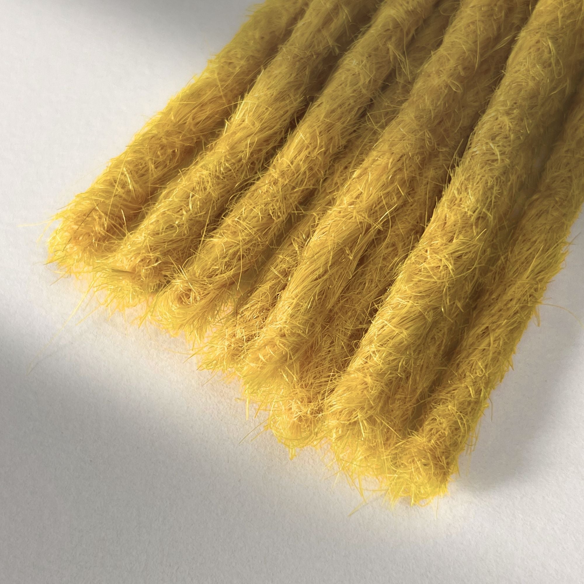 Tip detail of straight loc extensions with blunt ends in Lemon Yellow.