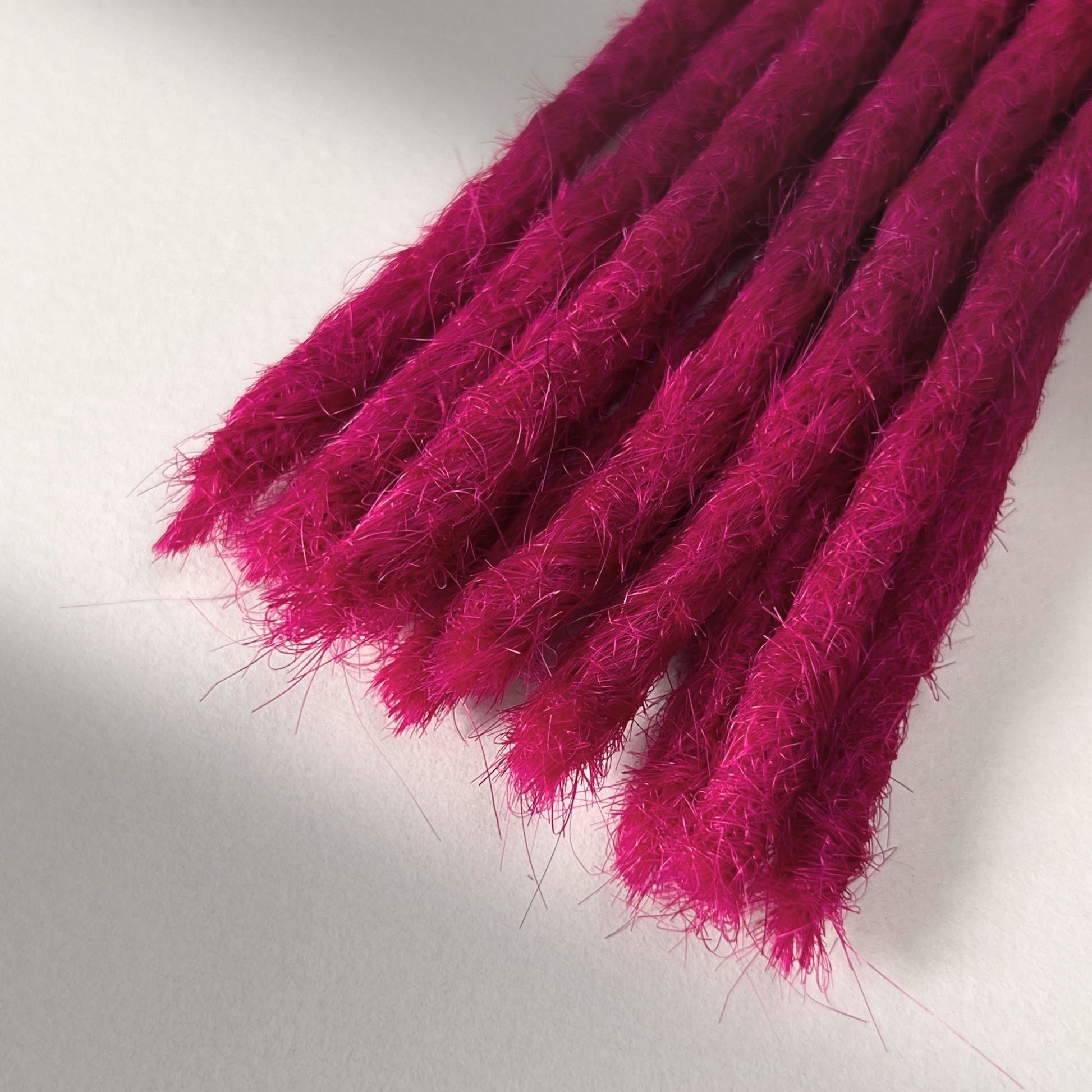 Tip detail of straight loc extensions with blunt ends in Magenta Pink.