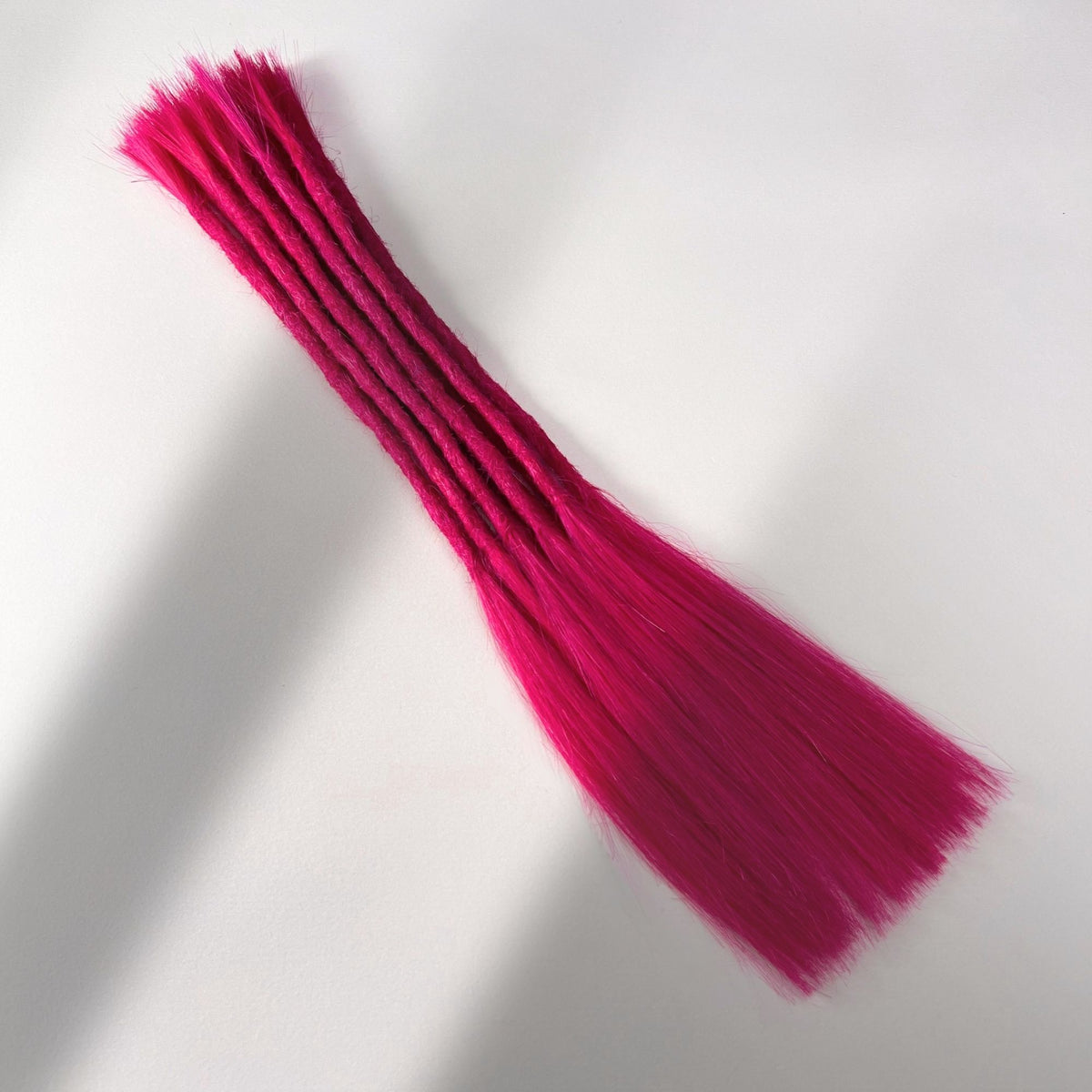 Full view of permanent straight loc extensions with long loose ends in Magenta Pink.