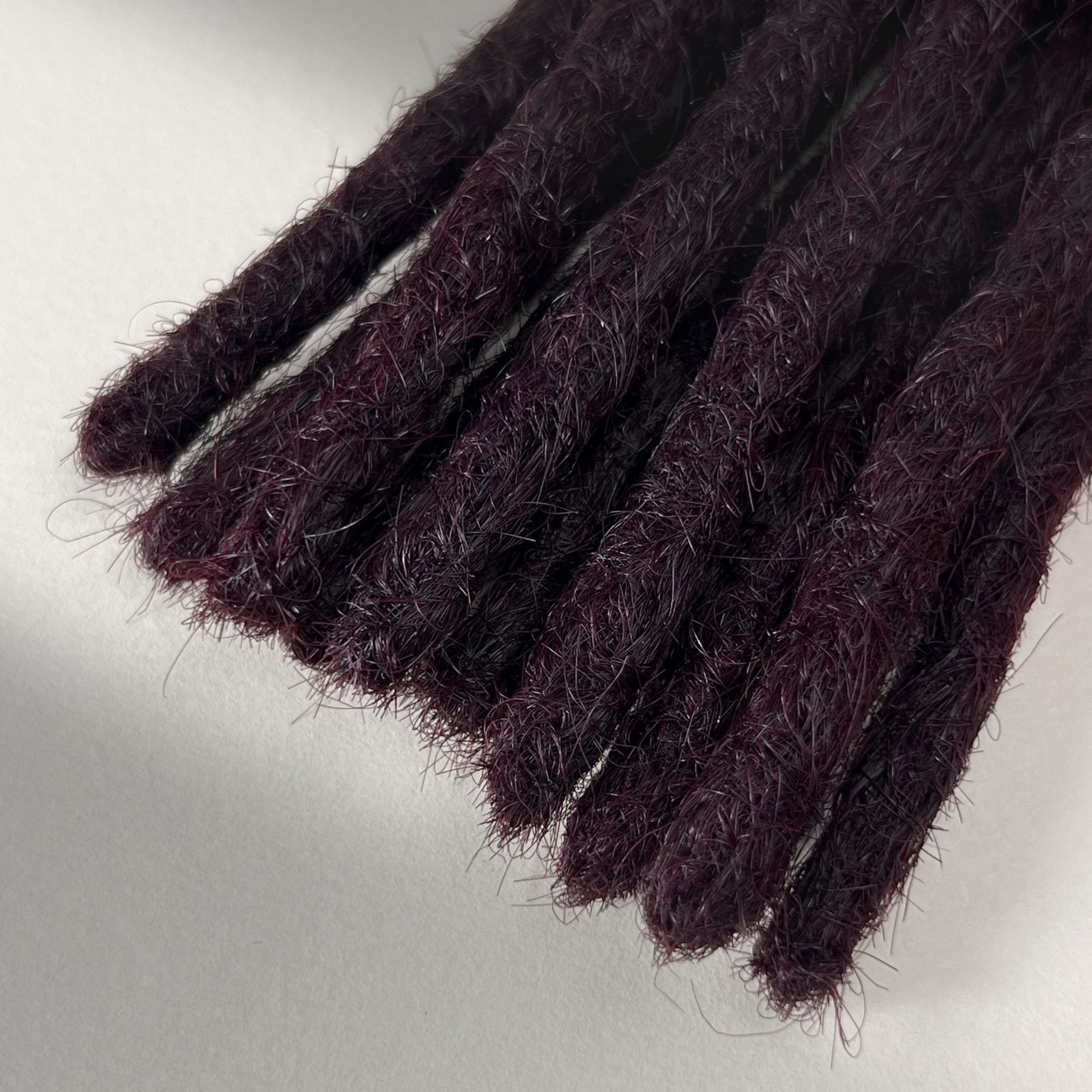 Tip detail of straight loc extensions with blunt ends in Warm Marsala Red.