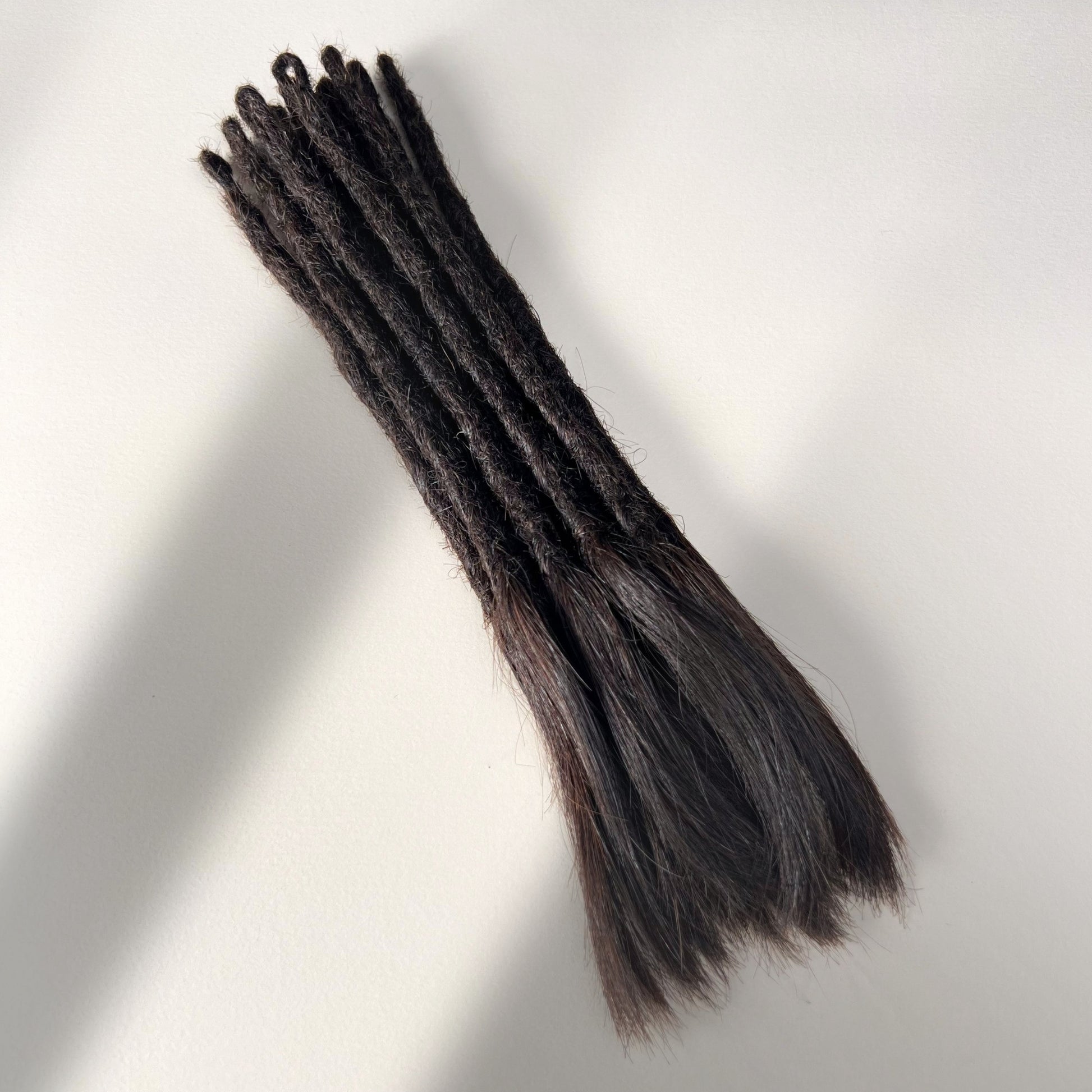 Full view of temporary single-ended straight loc extensions with open ends in Deep Brown.