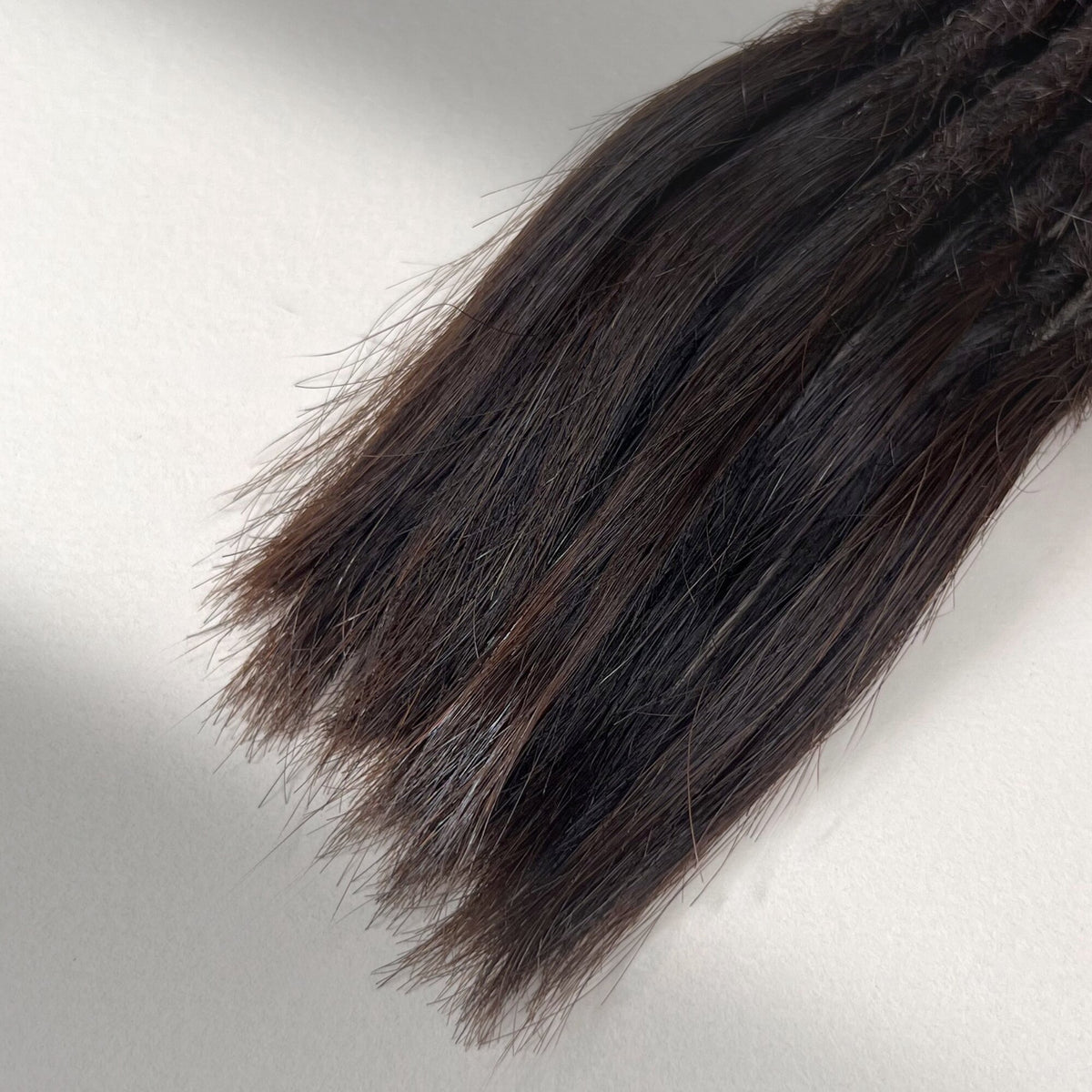 Tip detail of straight loc extensions with open ends in Deep Brown.