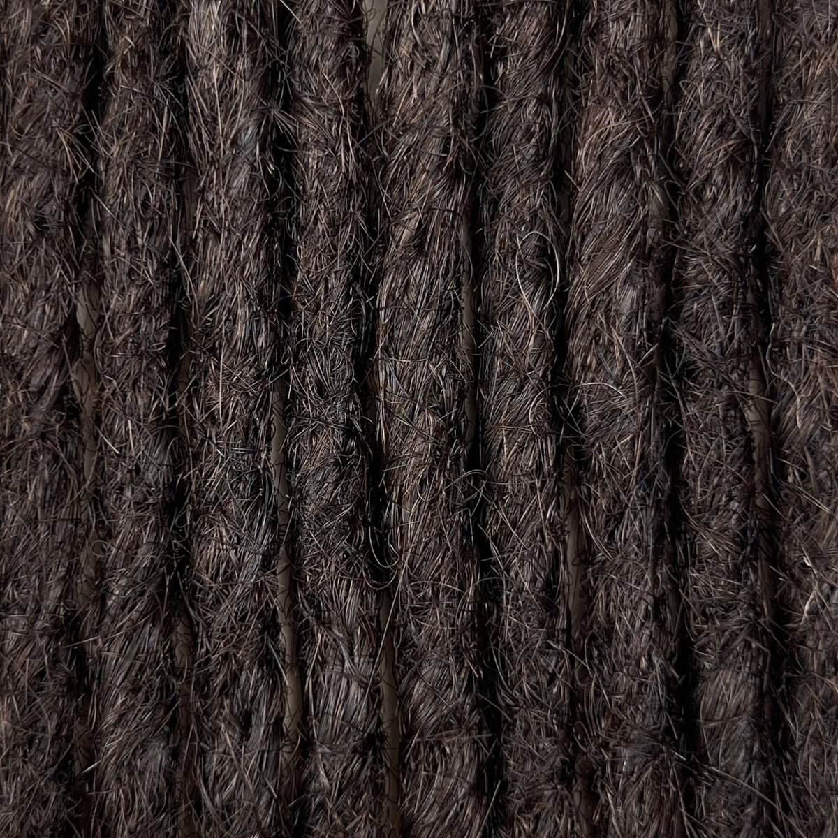 Close-up of straight loc extensions in Deep Brown, showing the texture and color.