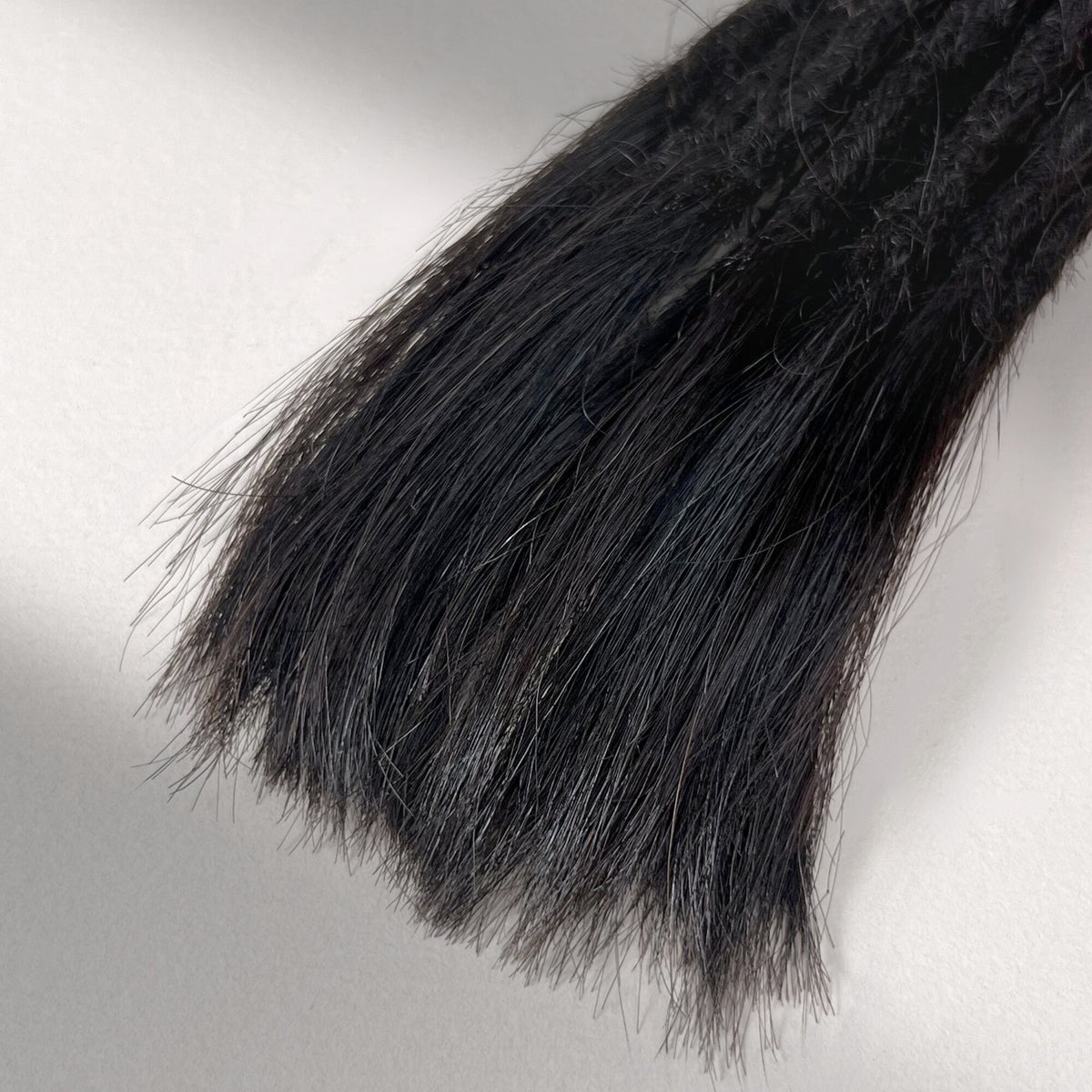 Tip detail of straight loc extensions with open ends in Dark Ash Brown.