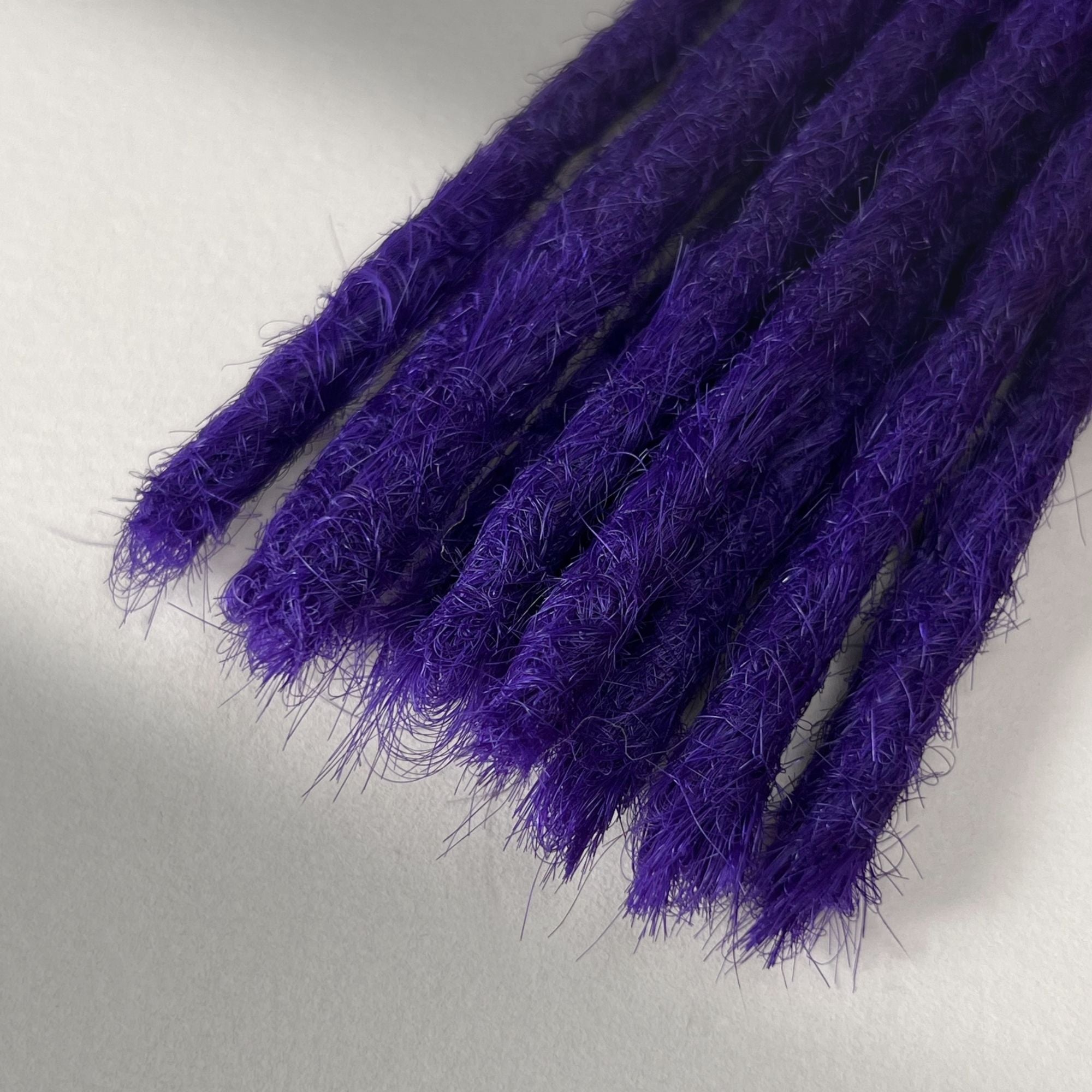Tip detail of straight loc extensions with blunt ends in Orchid Violet.