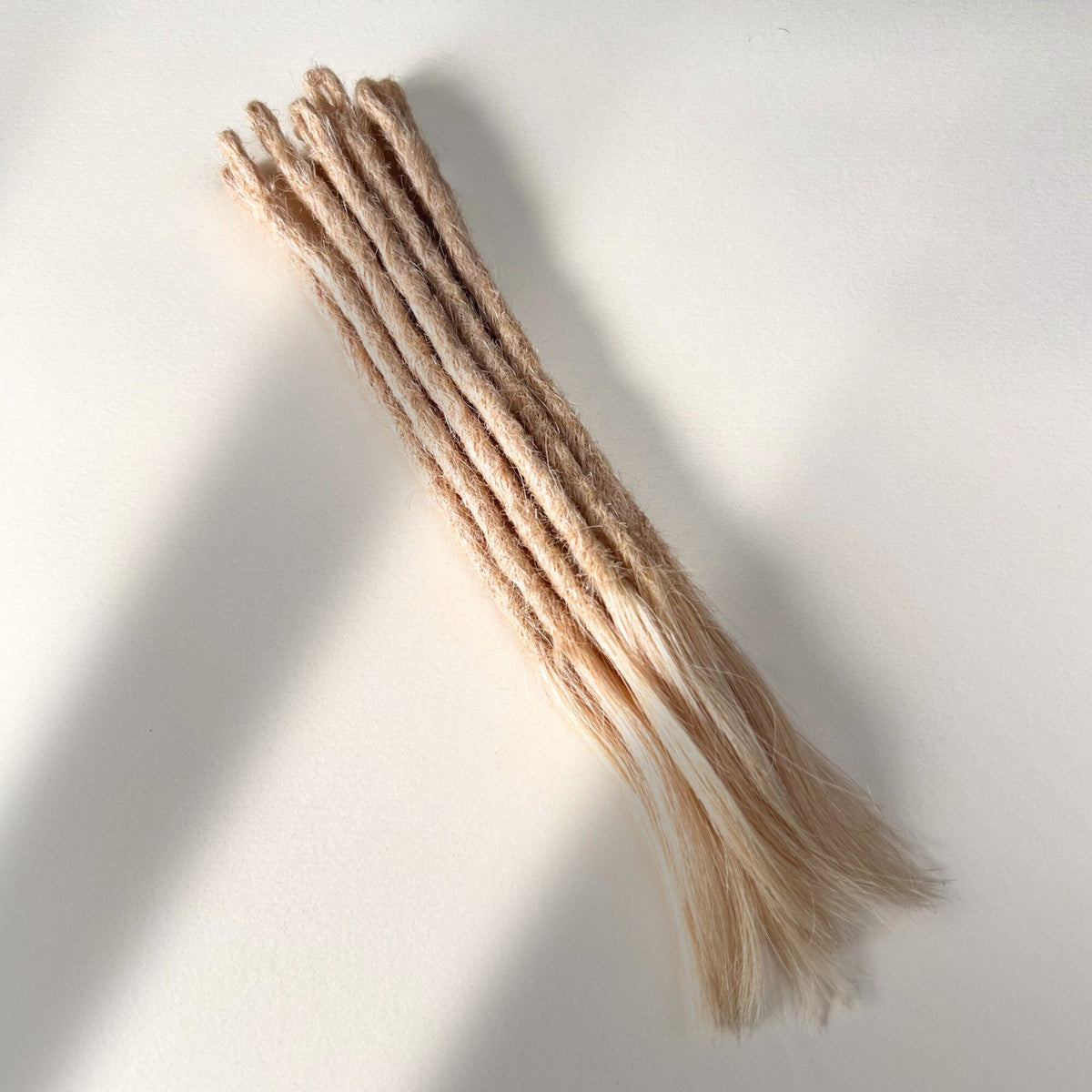 Full view of temporary single-ended straight loc extensions with open ends in Soft Rose Blonde.