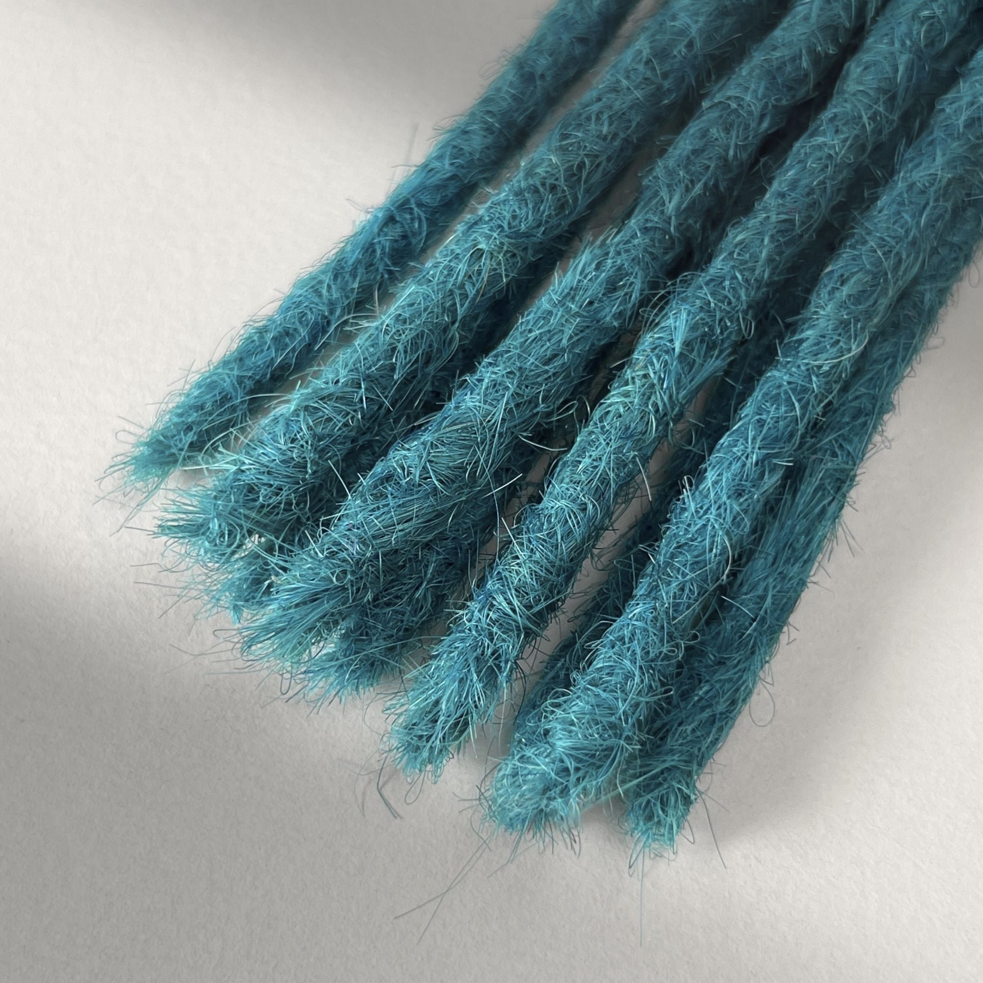 Tip detail of straight loc extensions with blunt ends in Frost Blue.
