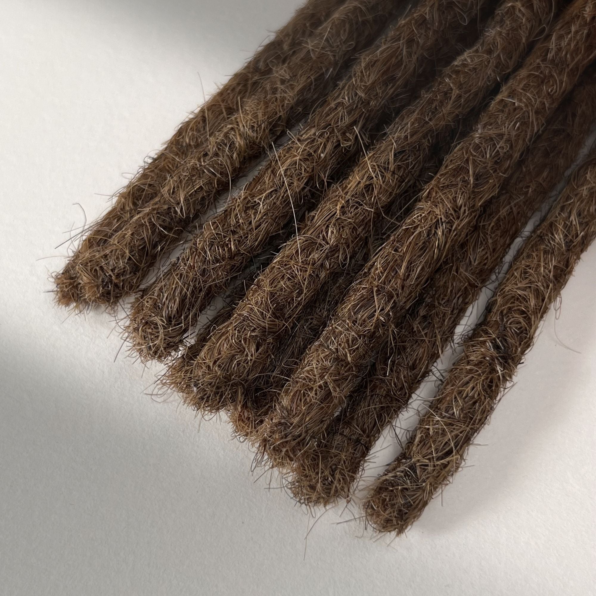 Tip detail of straight loc extensions with blunt ends in Warm Chestnut Brown.